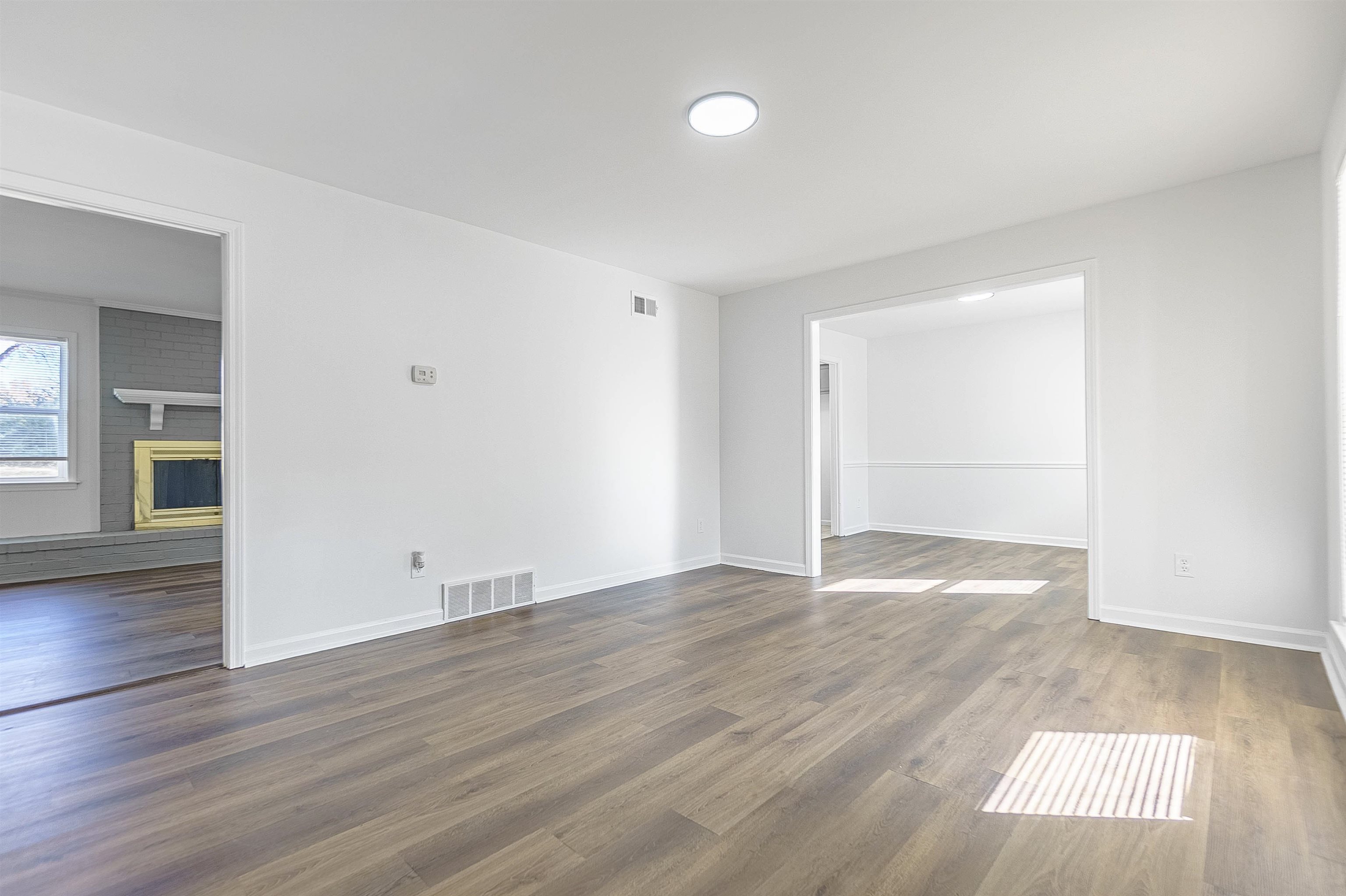 Empty room featuring a fireplace and dark wood-type flooring