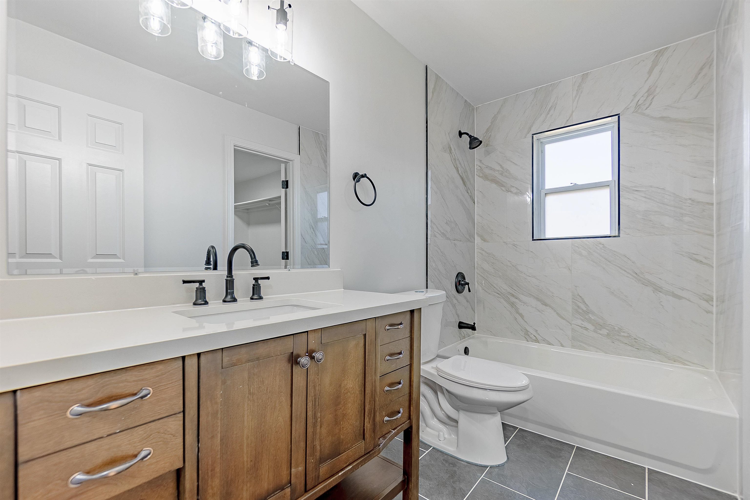 Full bathroom with tile patterned floors, vanity, tiled shower / bath combo, and toilet