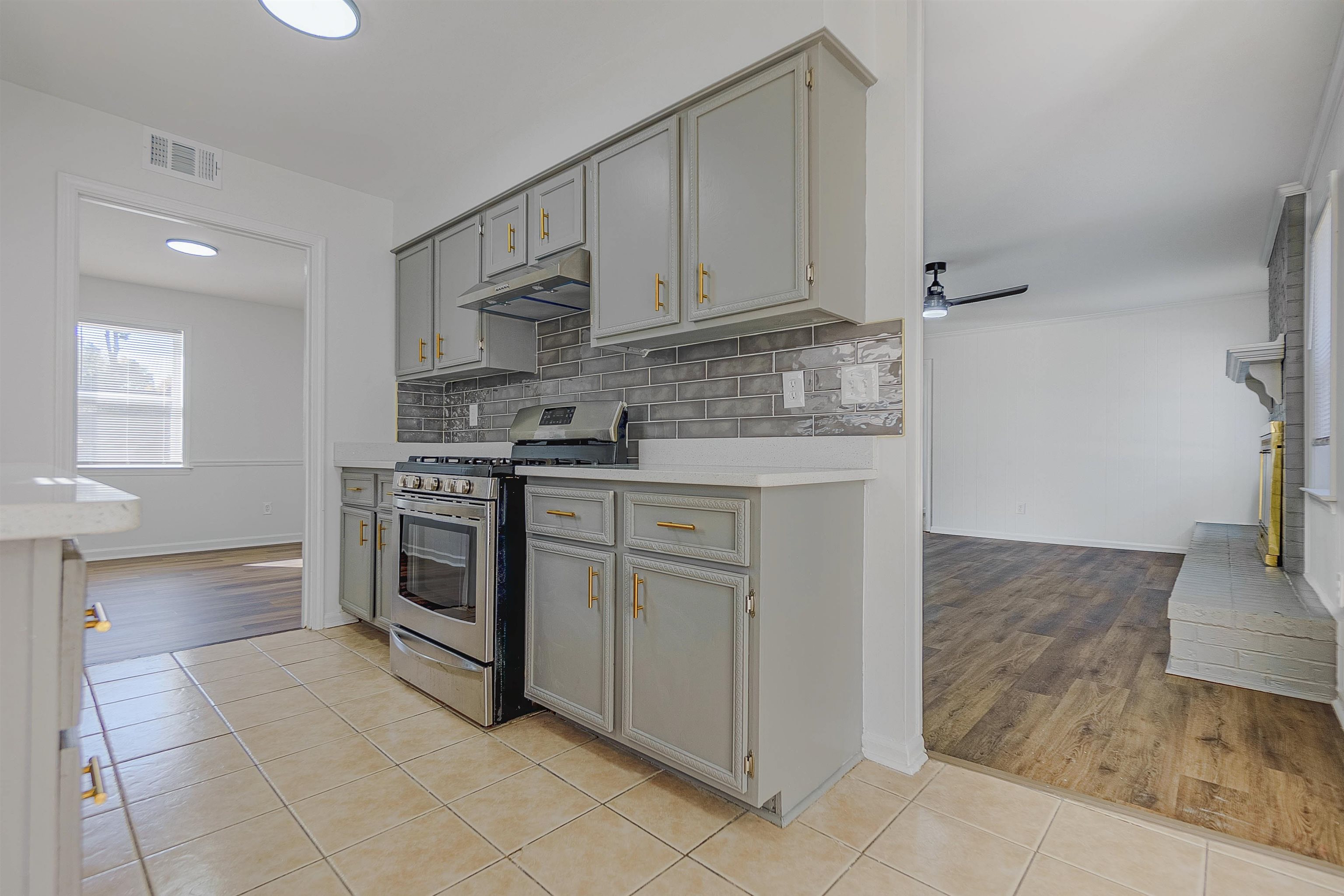 Kitchen with light hardwood / wood-style flooring, ceiling fan, gray cabinetry, and stainless steel range with gas stovetop