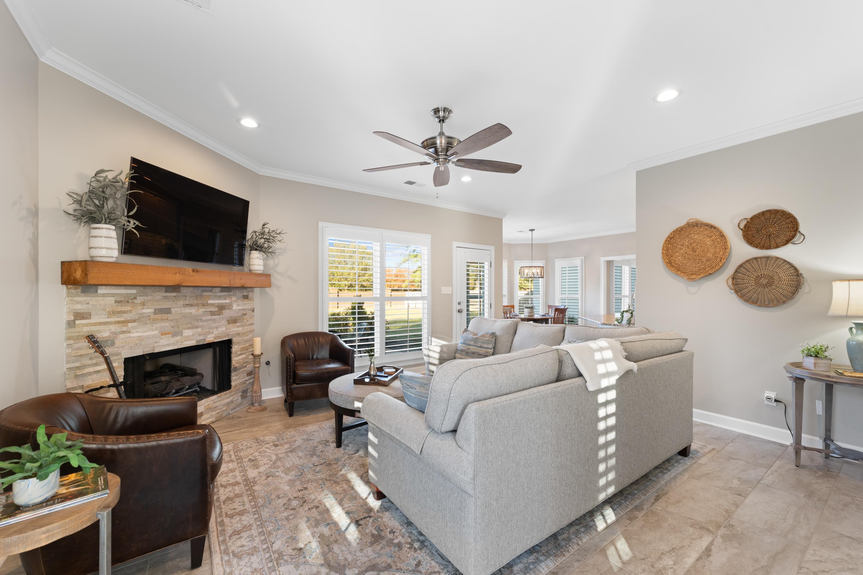 Living room with ceiling fan, a fireplace, and ornamental molding