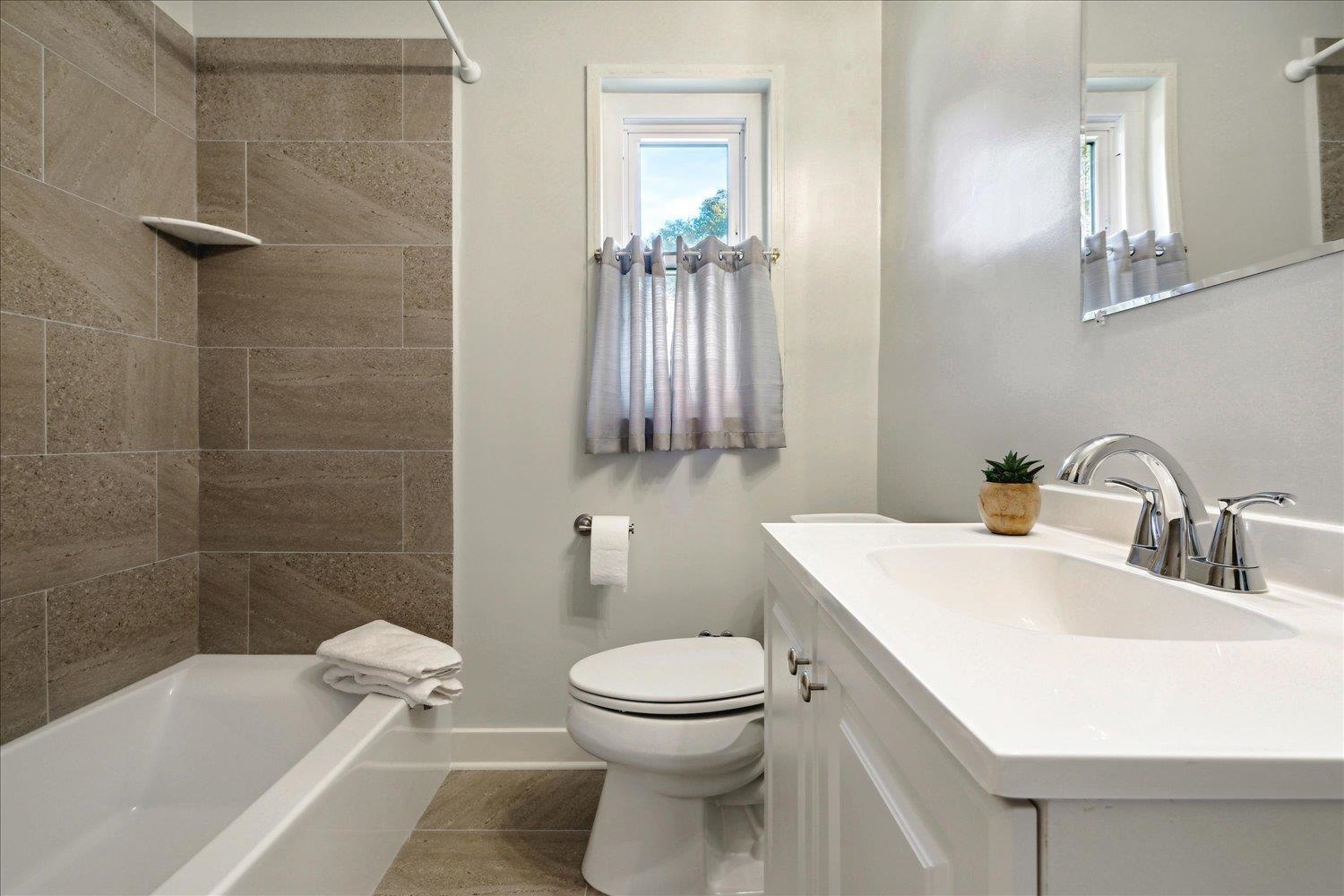 Full bathroom featuring tile patterned flooring, vanity, tiled shower / bath combo, and toilet