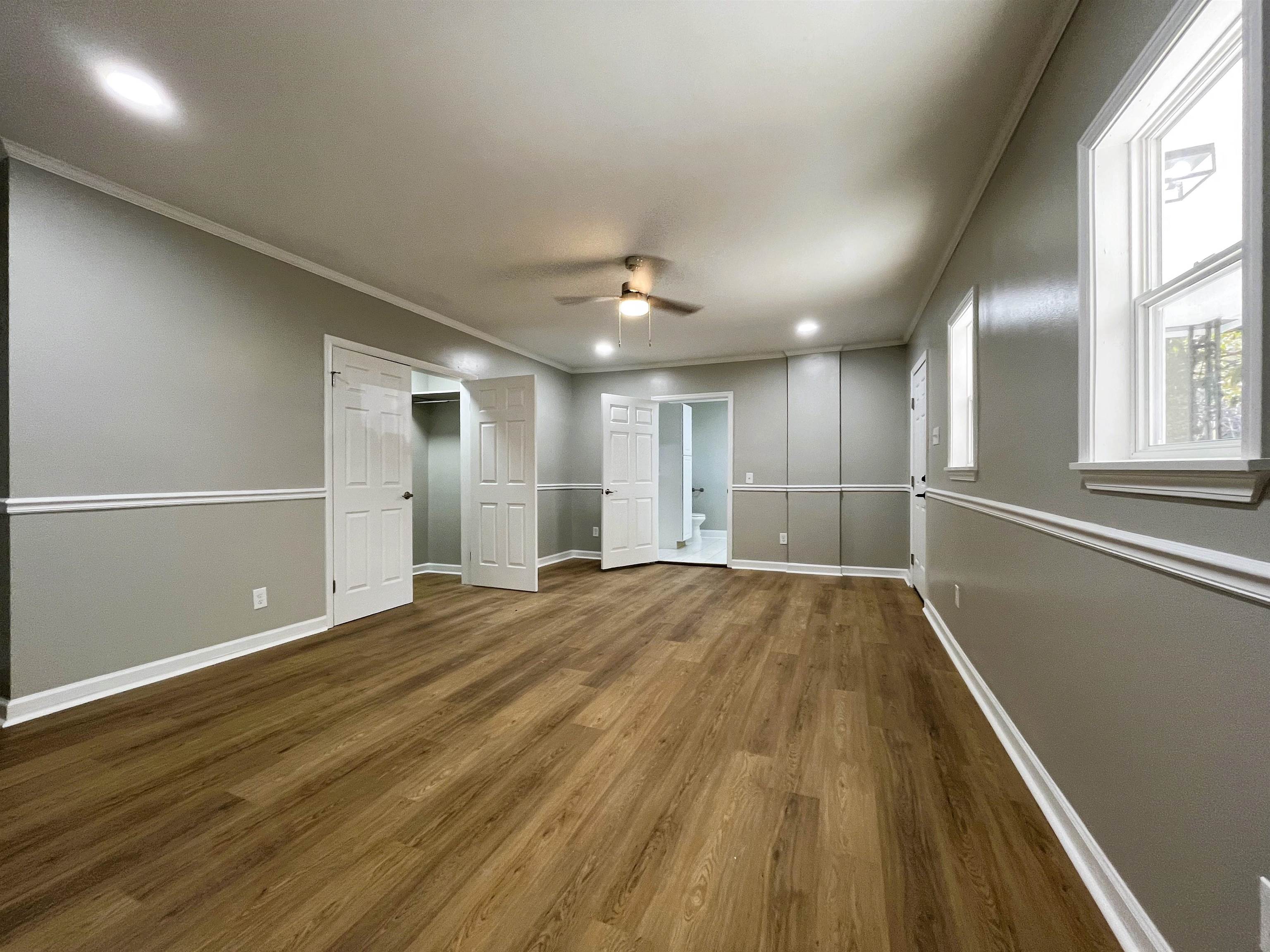 Unfurnished bedroom with ceiling fan, wood-type flooring, and ornamental molding