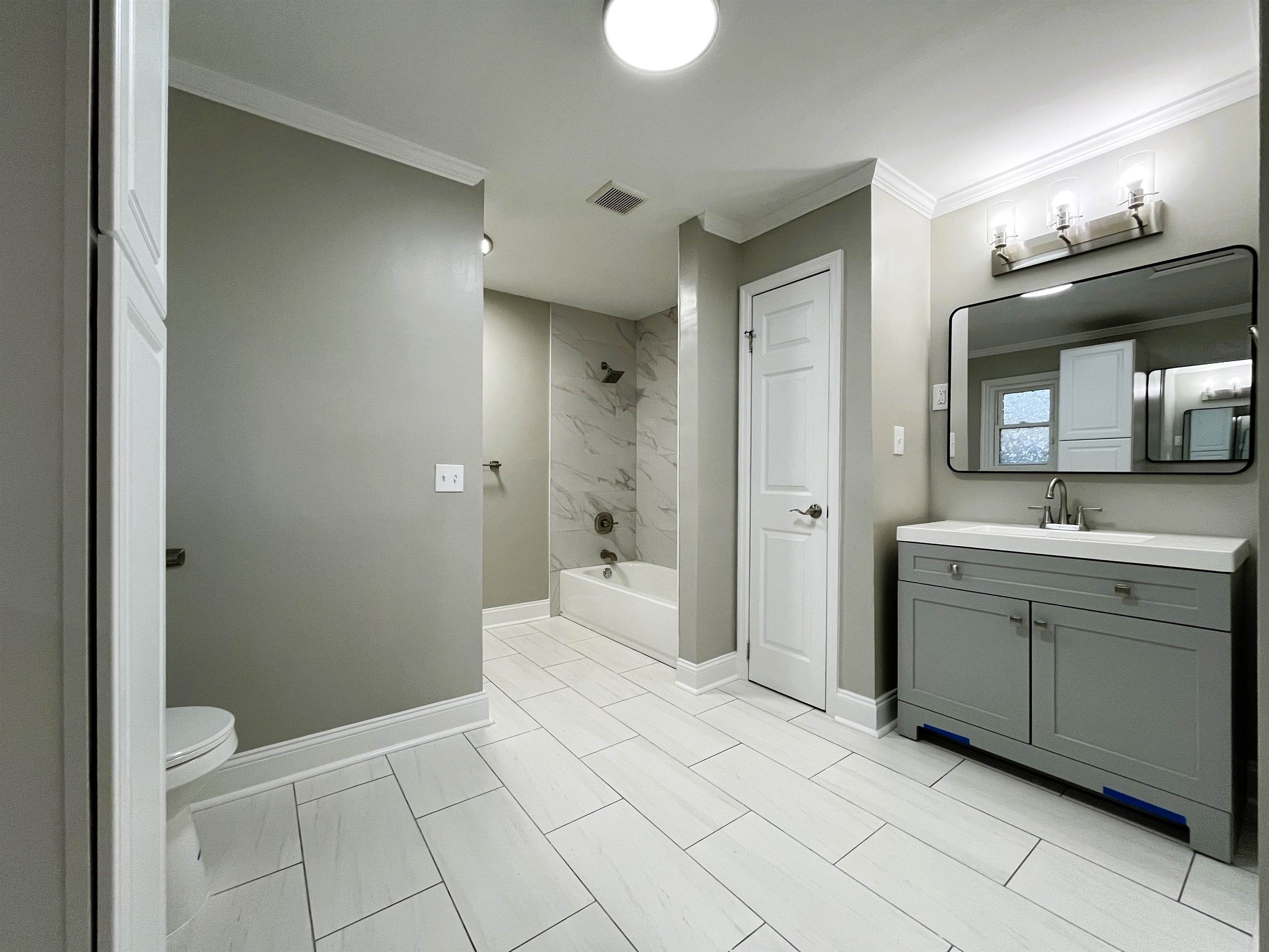 Full bathroom featuring tiled shower / bath, crown molding, vanity, and toilet