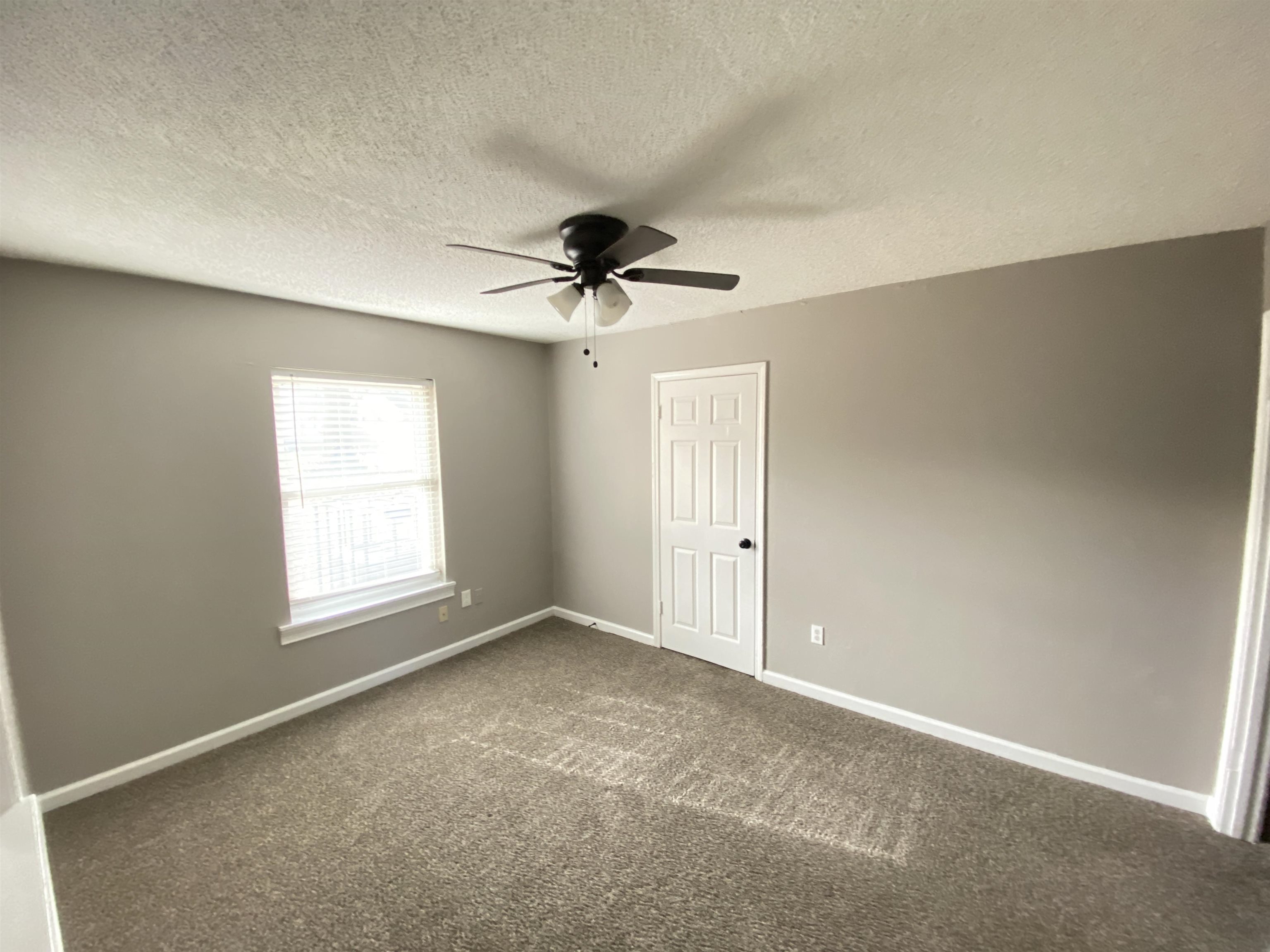 Spare room featuring ceiling fan, a textured ceiling, and dark colored carpet