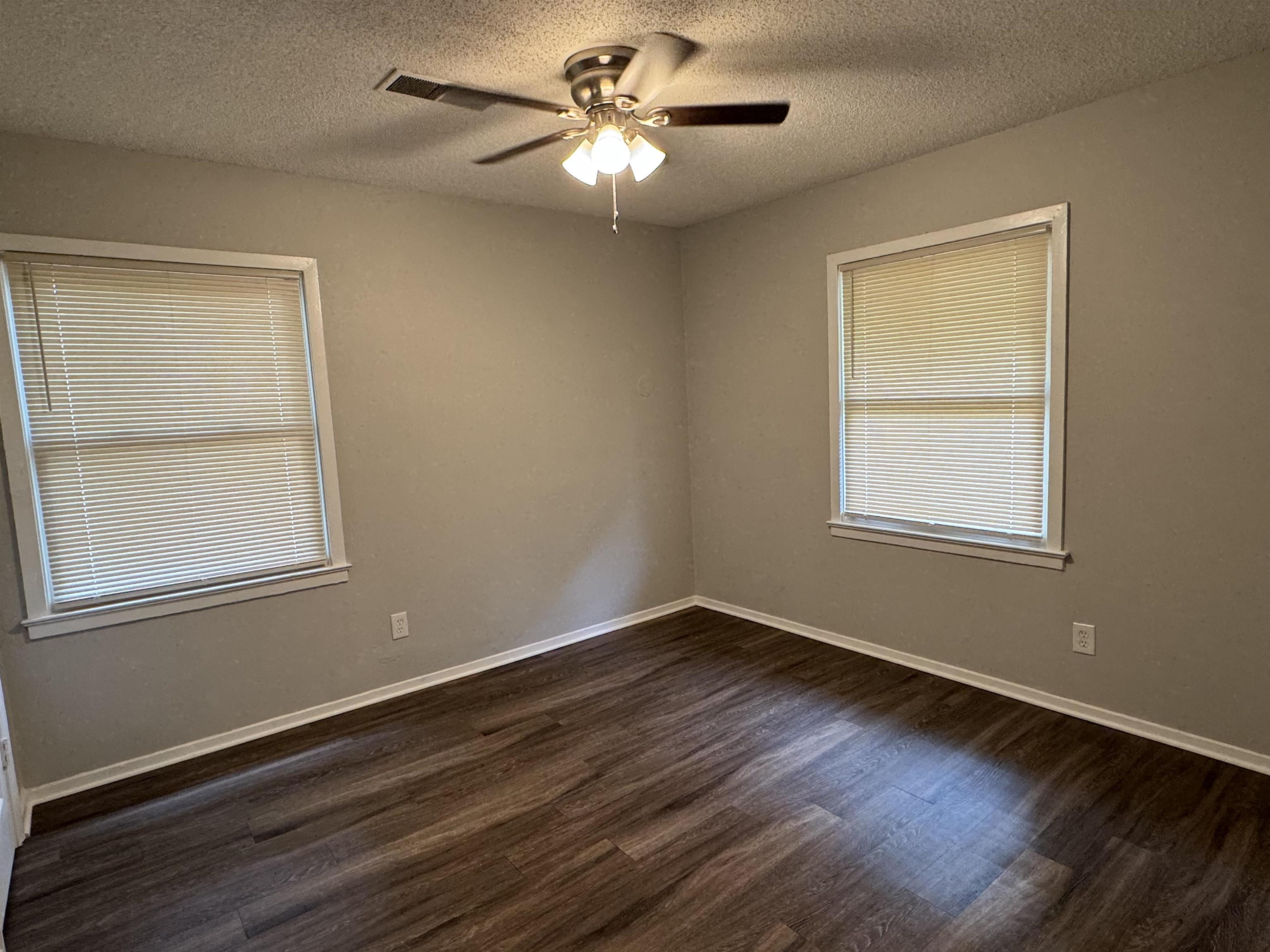 Spare room featuring ceiling fan, dark hardwood / wood-style flooring, and a textured ceiling