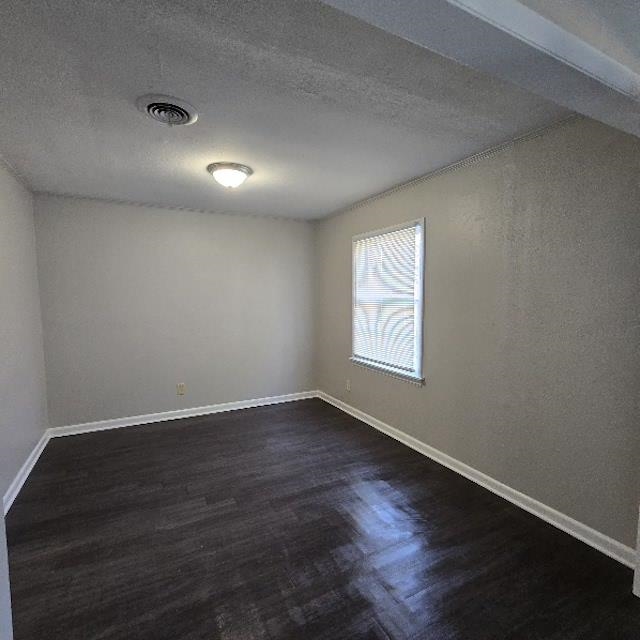 Unfurnished room featuring dark hardwood / wood-style flooring and a textured ceiling