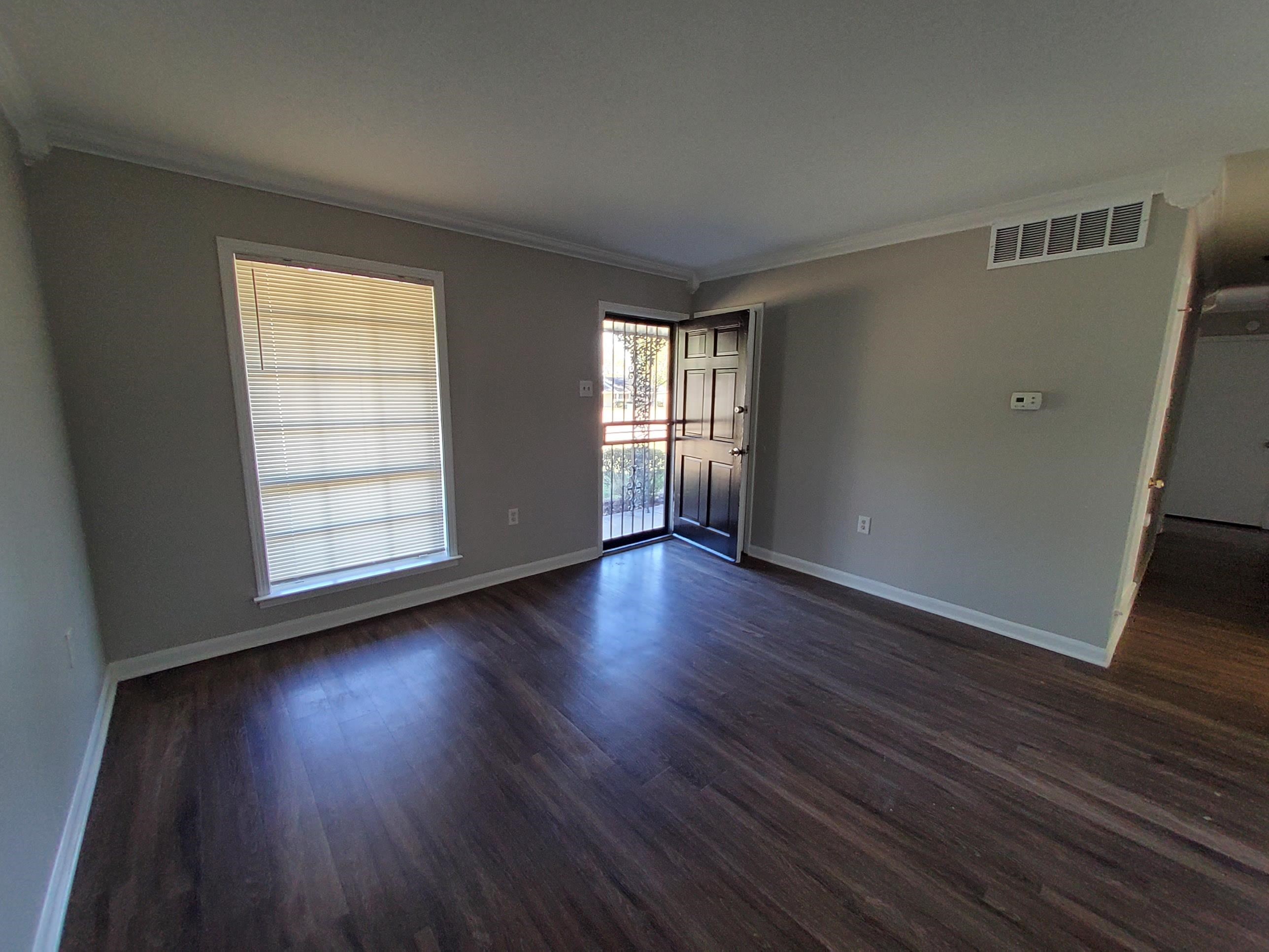 Empty room featuring dark hardwood / wood-style floors and crown molding