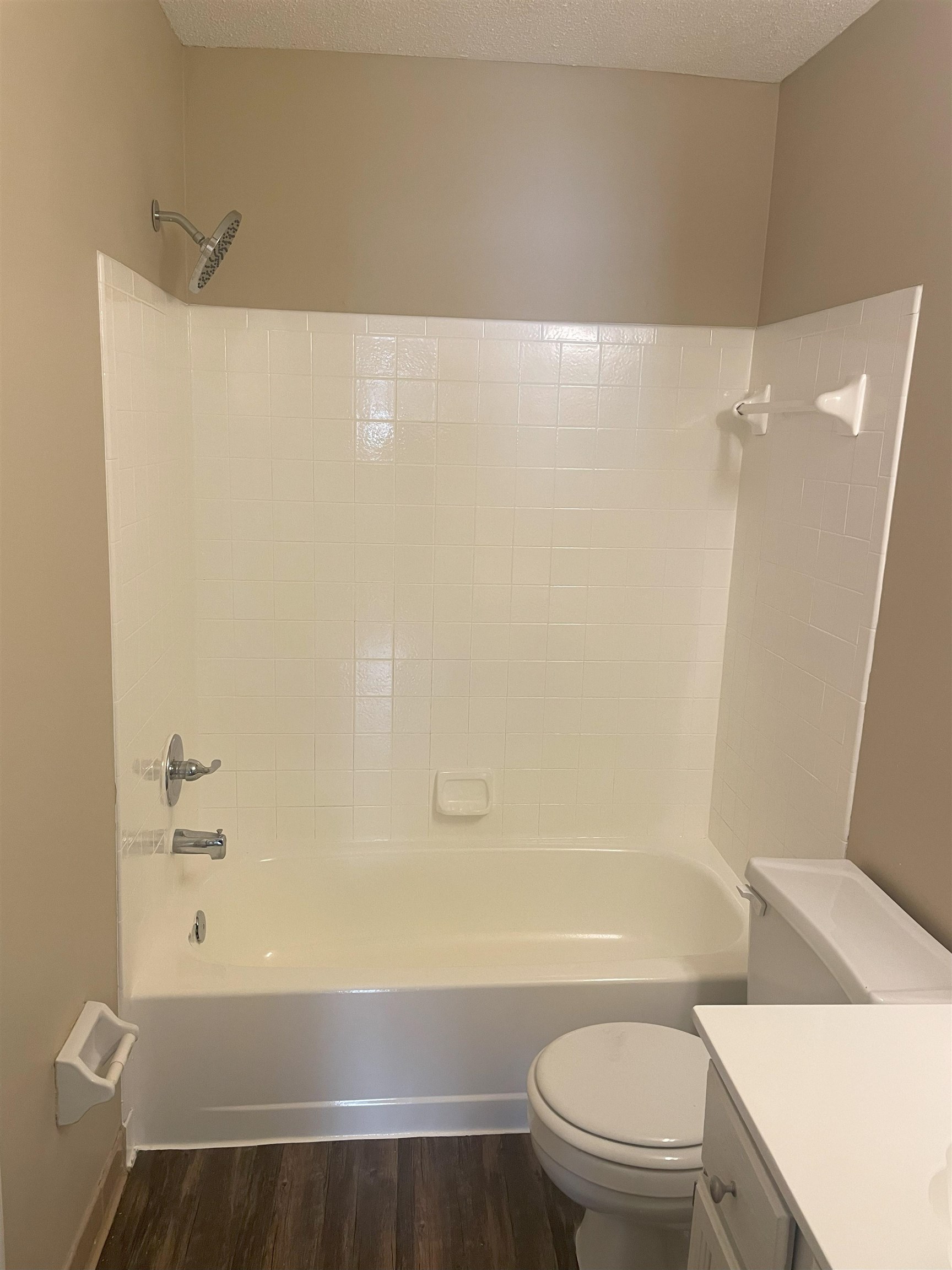 Full bathroom featuring hardwood / wood-style floors, shower / bathing tub combination, a textured ceiling, and toilet