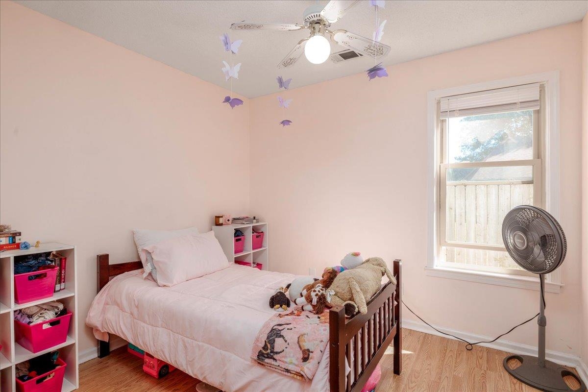 Bedroom with ceiling fan, light hardwood / wood-style flooring, and multiple windows