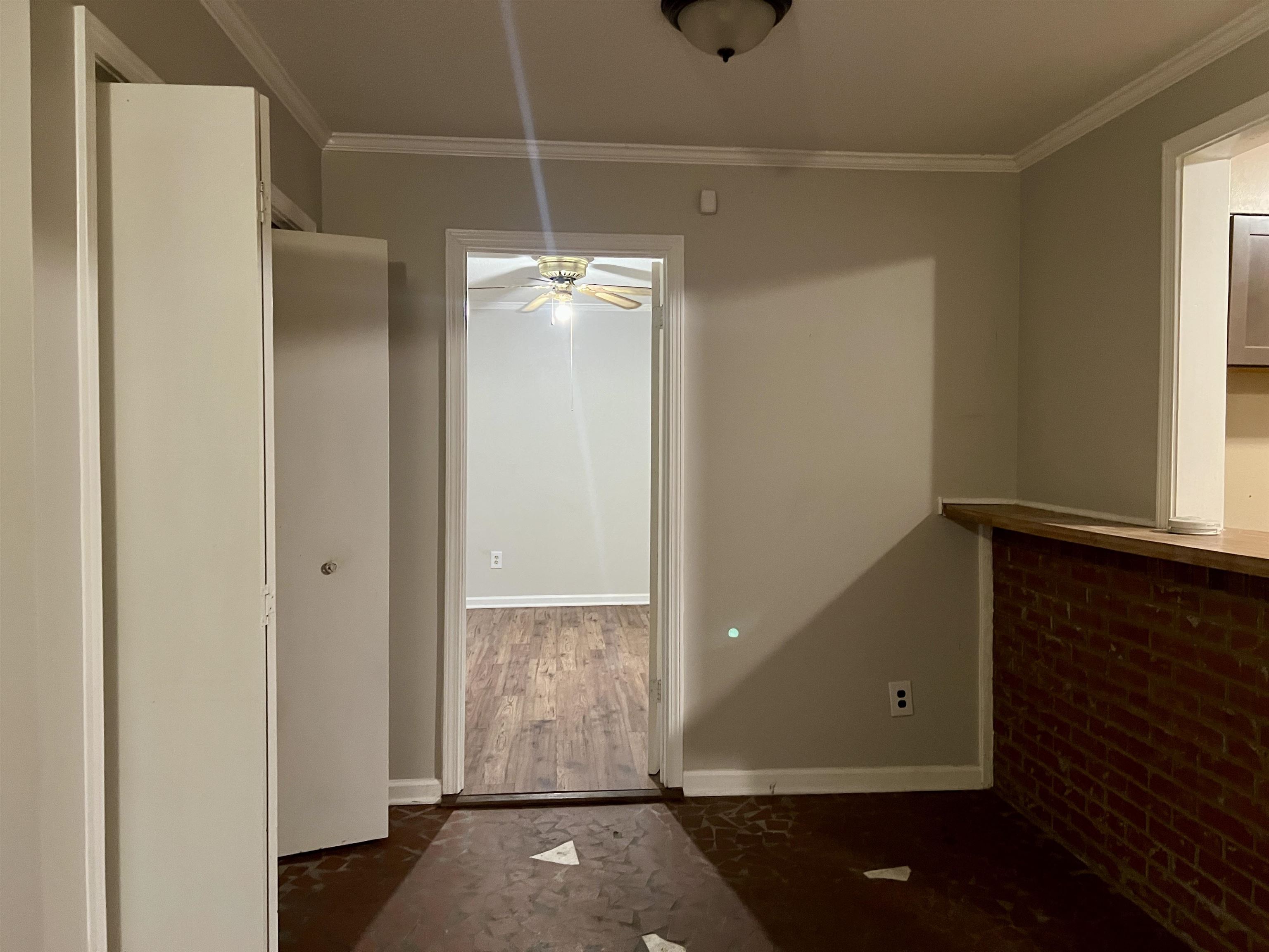 Interior space with ornamental molding, dark wood-type flooring, and brick wall