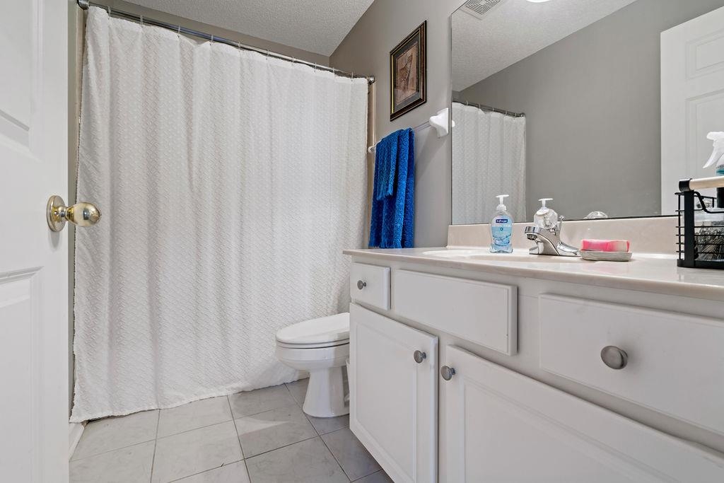 Bathroom with tile patterned flooring, vanity, a textured ceiling, and toilet