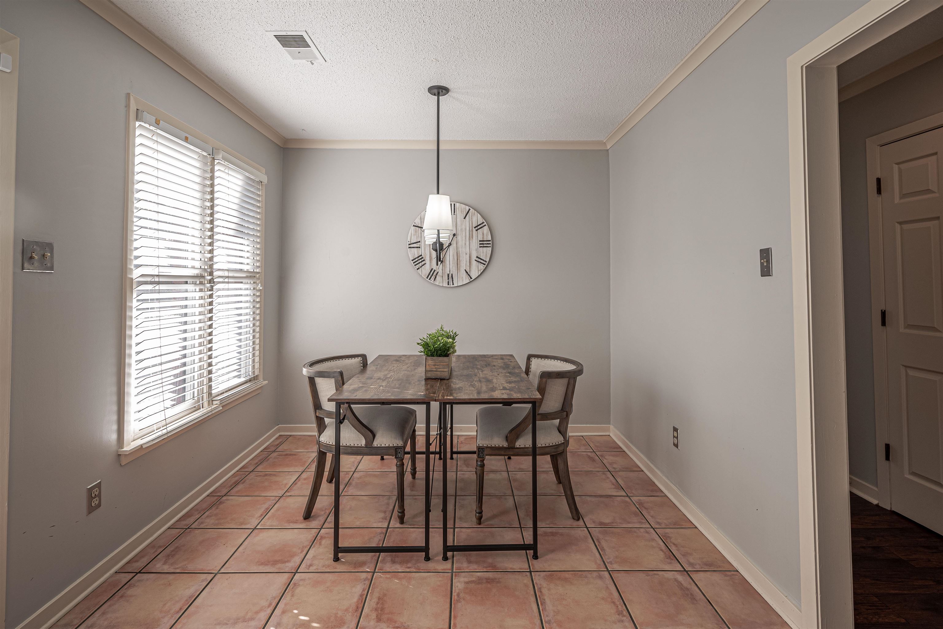 Tiled dining room featuring a textured ceiling and crown molding