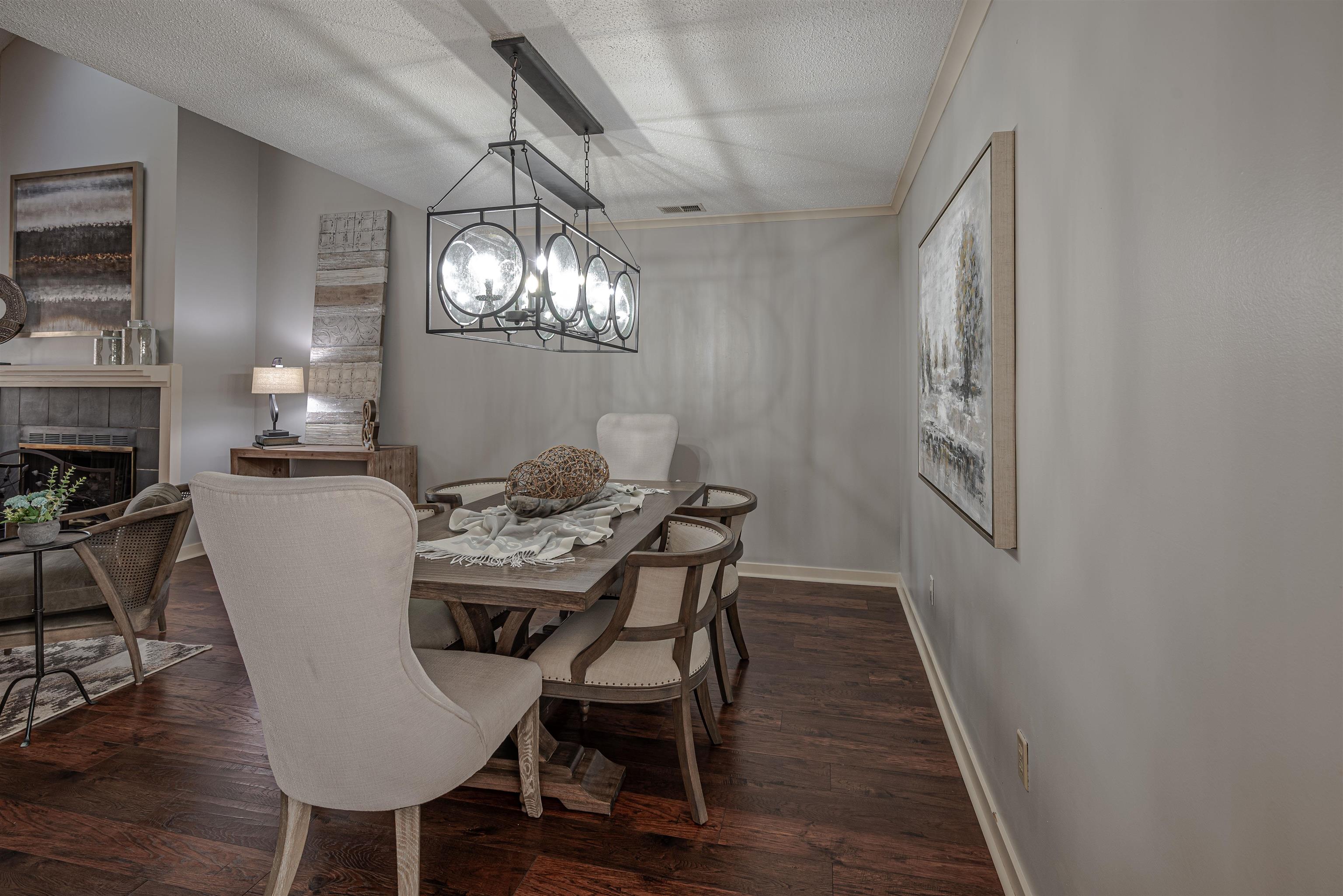 Dining room with a textured ceiling, a tiled fireplace, dark hardwood / wood-style floors, and ornamental molding