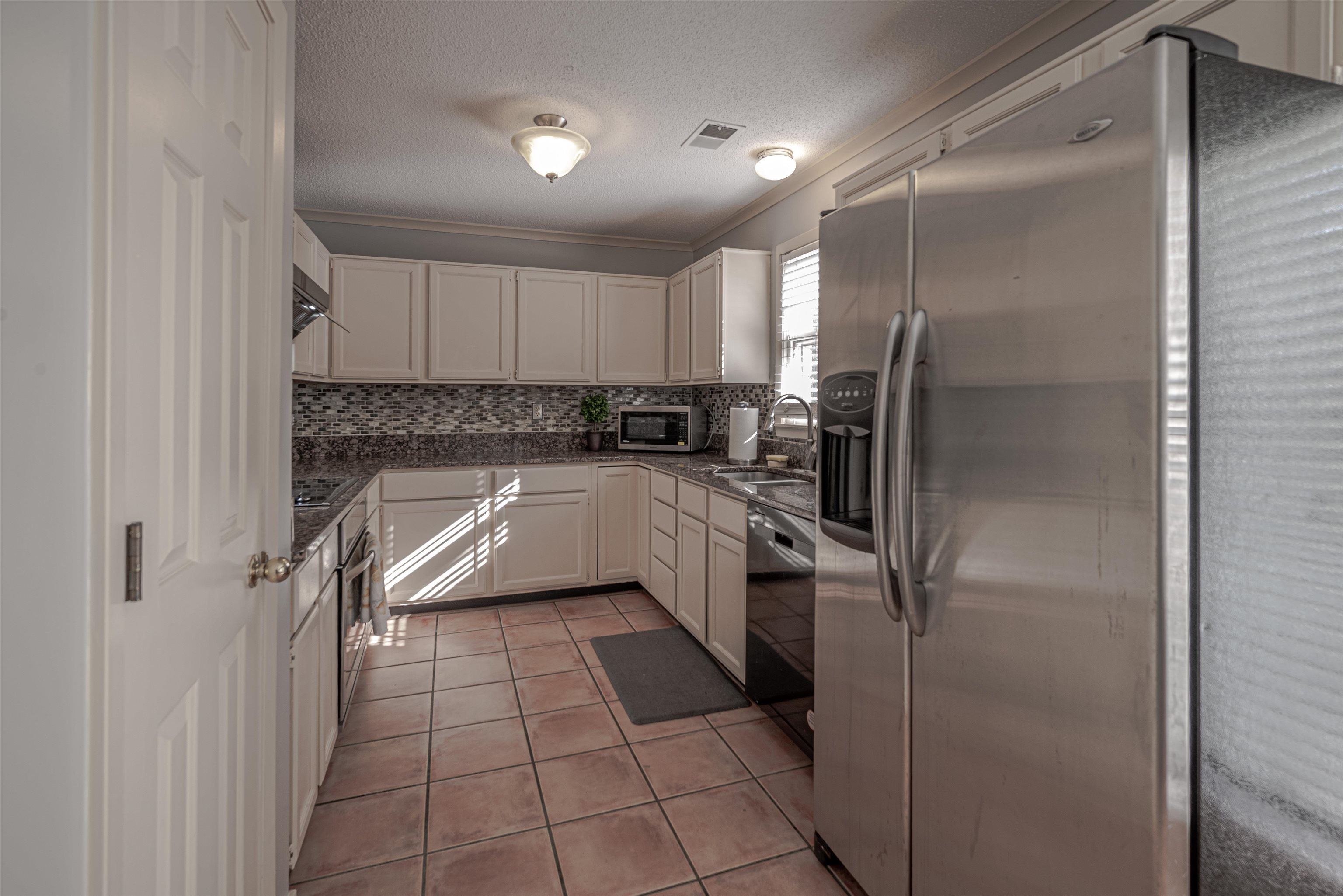 Kitchen with sink, crown molding, decorative backsplash, white cabinetry, and stainless steel appliances