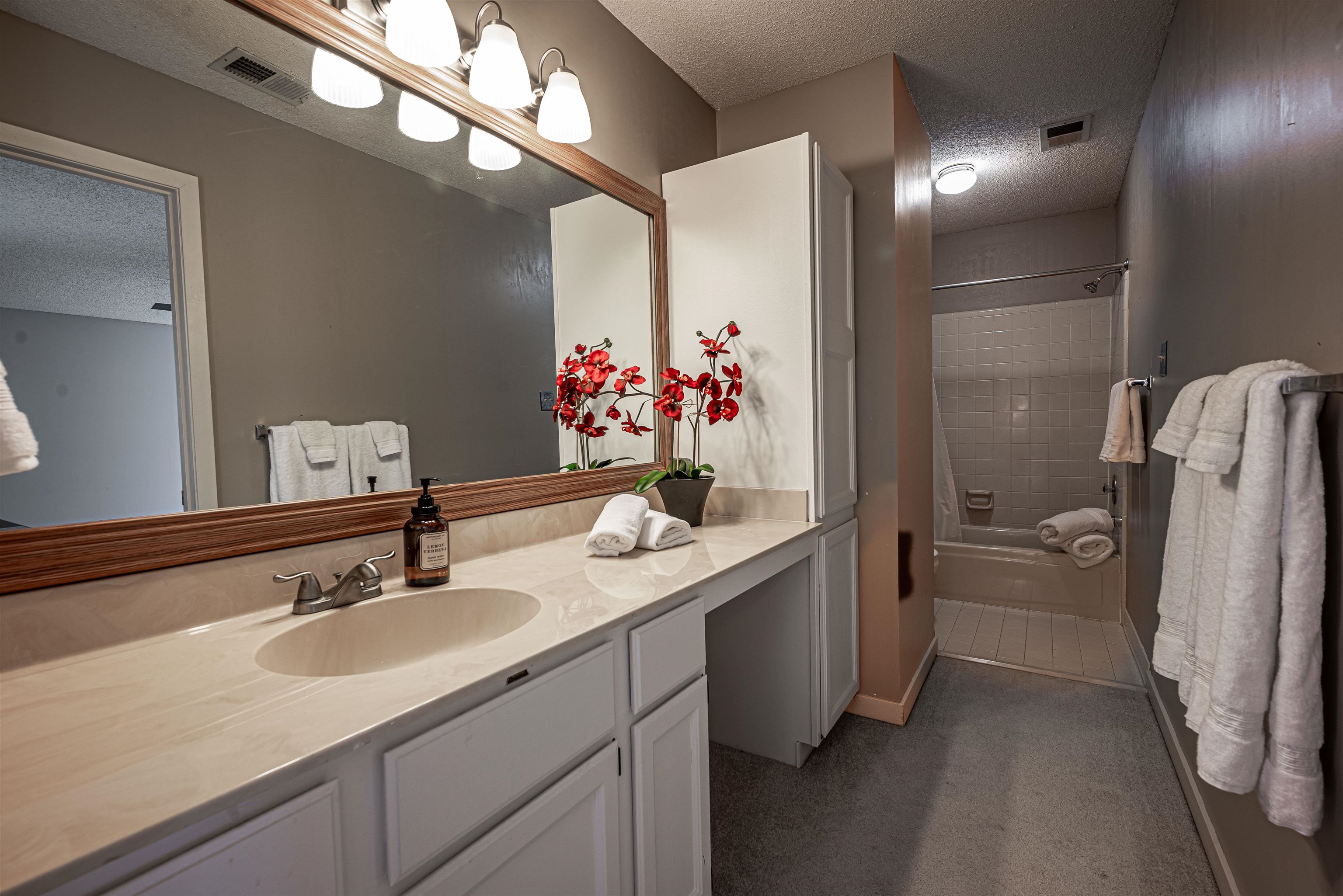 Bathroom featuring vanity, a textured ceiling, and tiled shower / bath