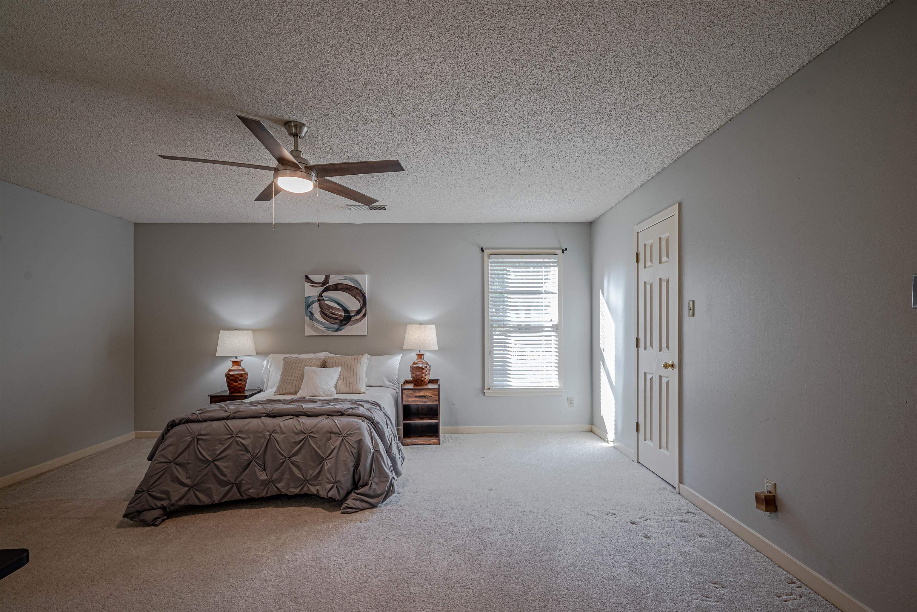 Carpeted bedroom with a textured ceiling and ceiling fan