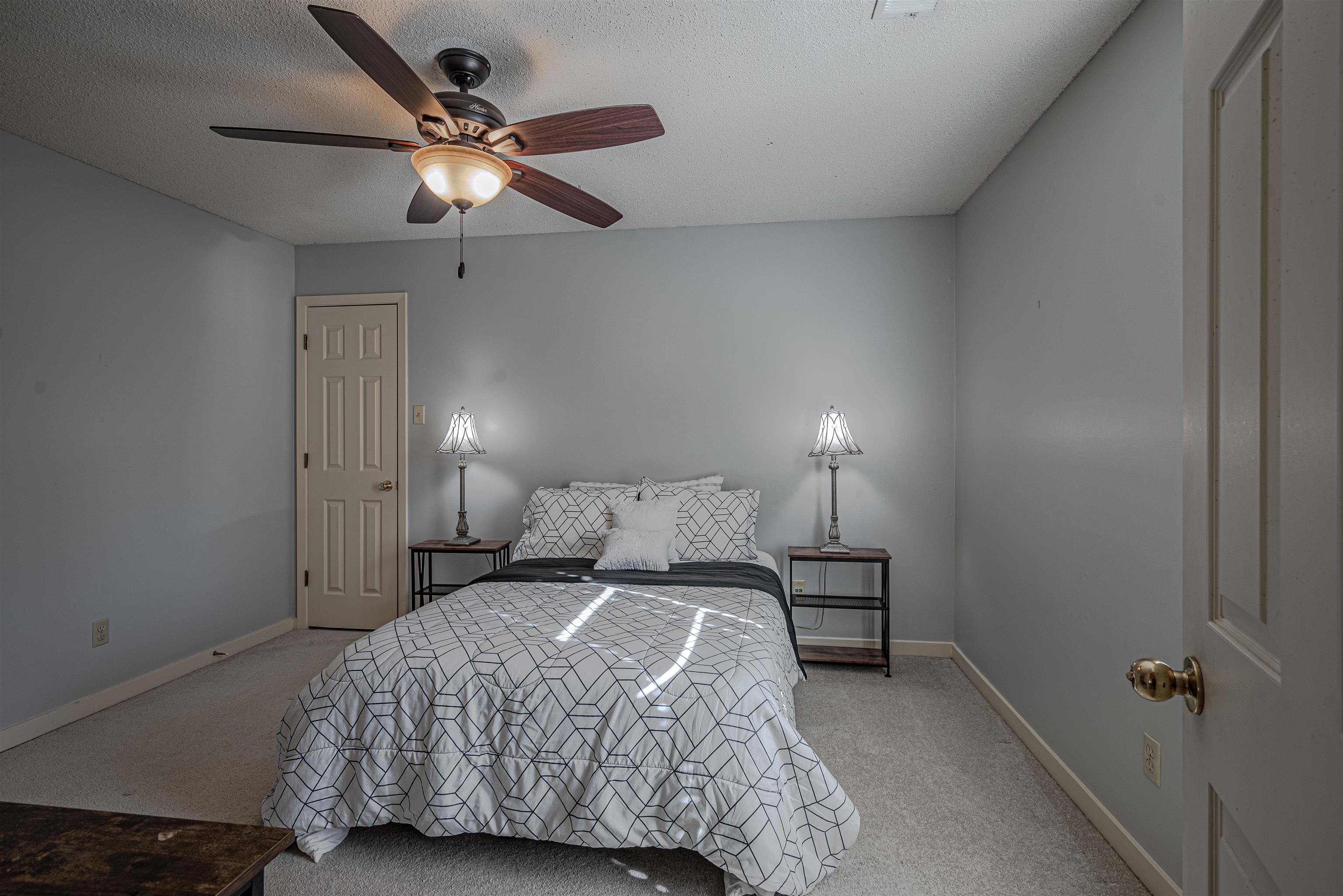 Carpeted bedroom with ceiling fan and a textured ceiling