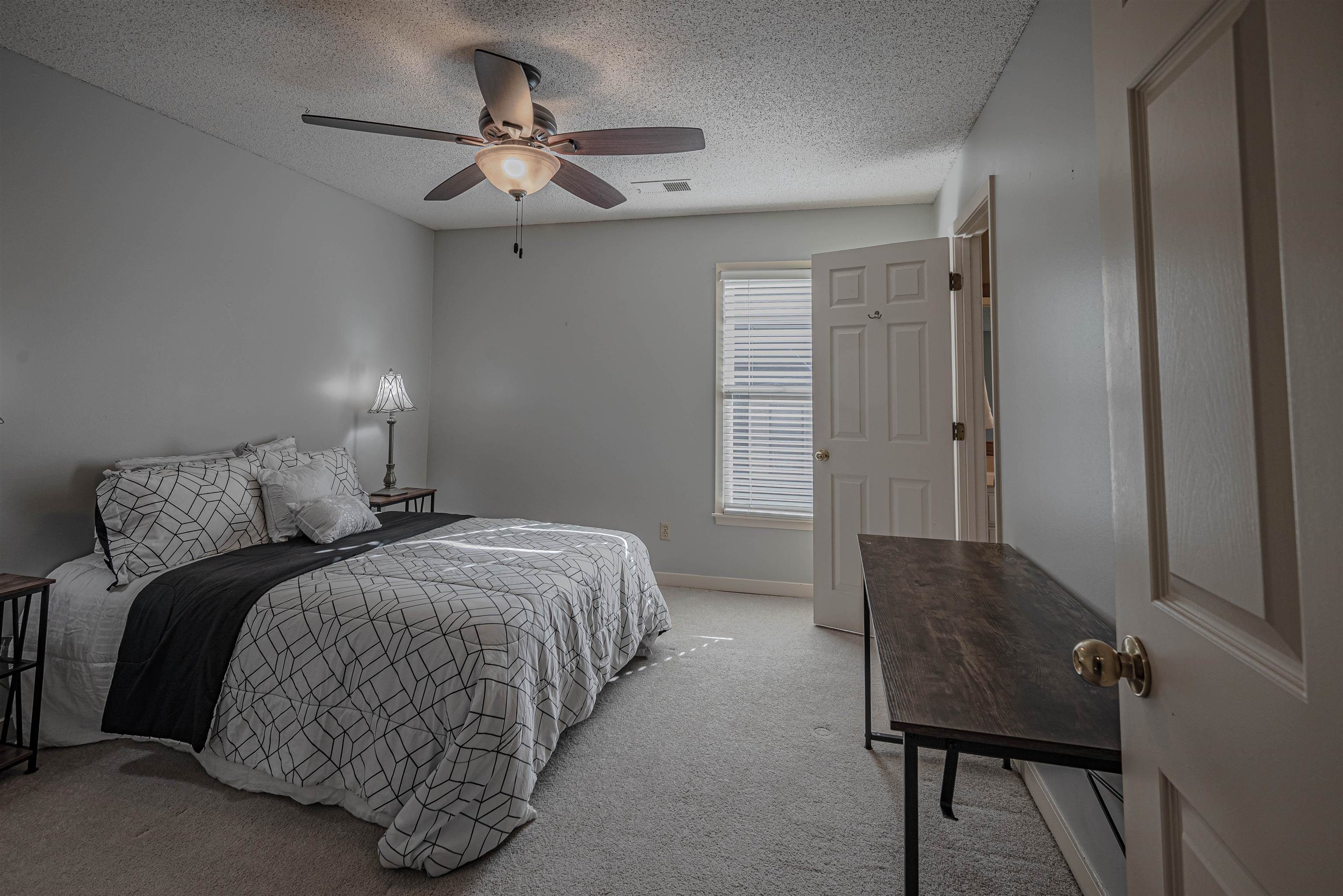 Carpeted bedroom featuring ceiling fan and a textured ceiling
