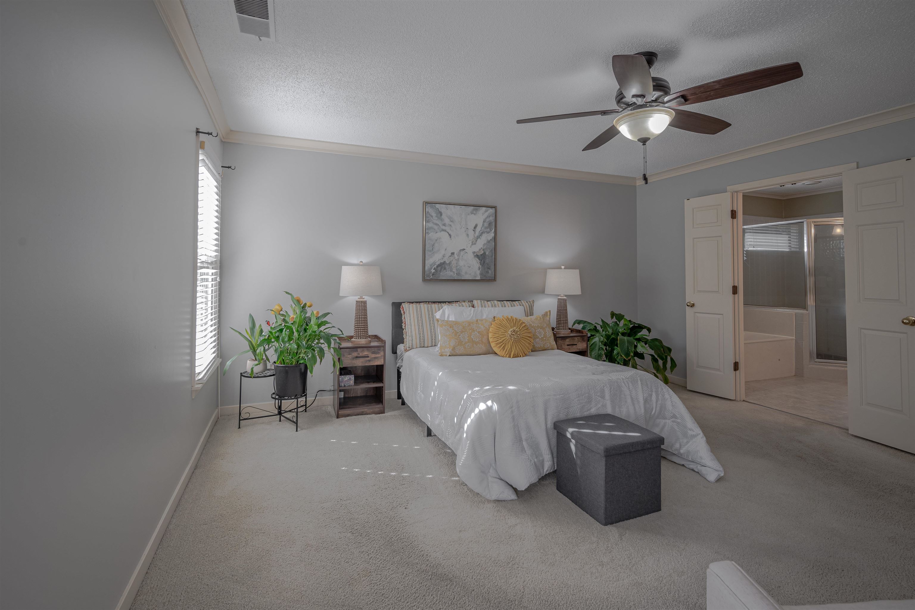 Bedroom with ceiling fan, light colored carpet, and ornamental molding