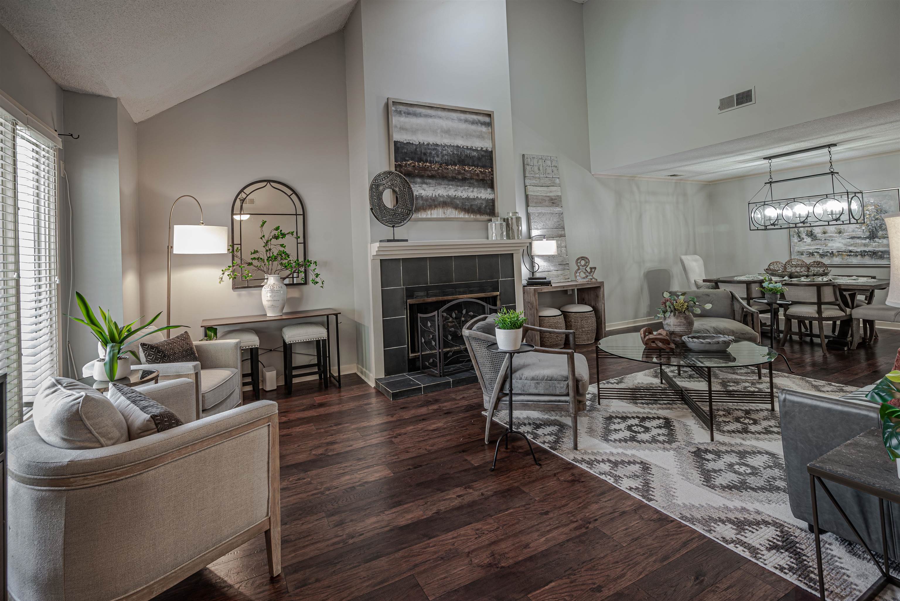 Living room with a fireplace, high vaulted ceiling, and dark wood-type flooring