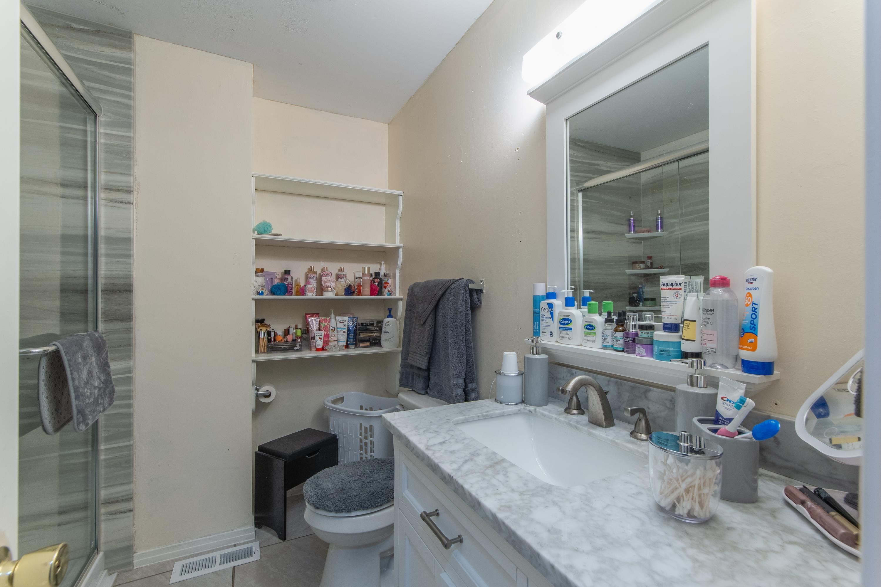 Bathroom with tile patterned floors, walk in shower, vanity, and toilet