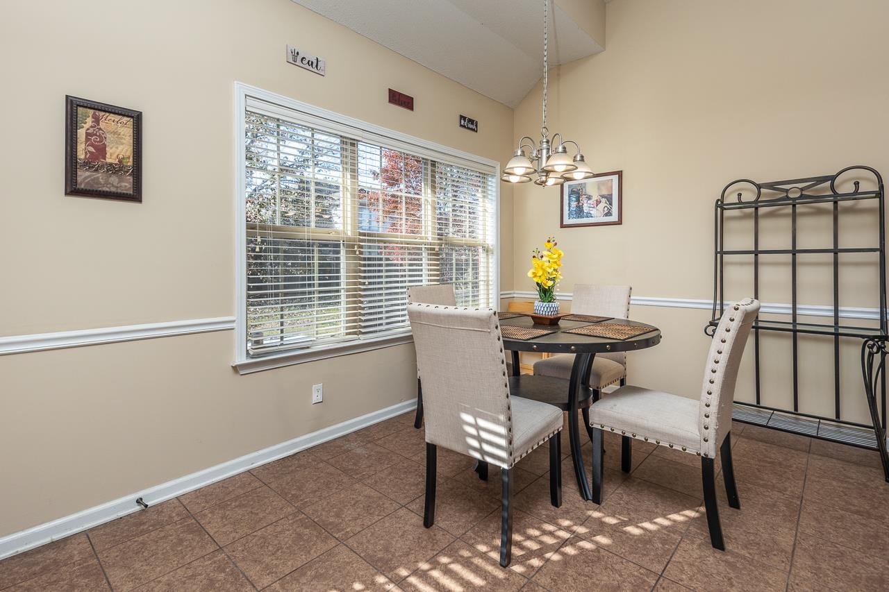 Tiled dining space with a notable chandelier and lofted ceiling