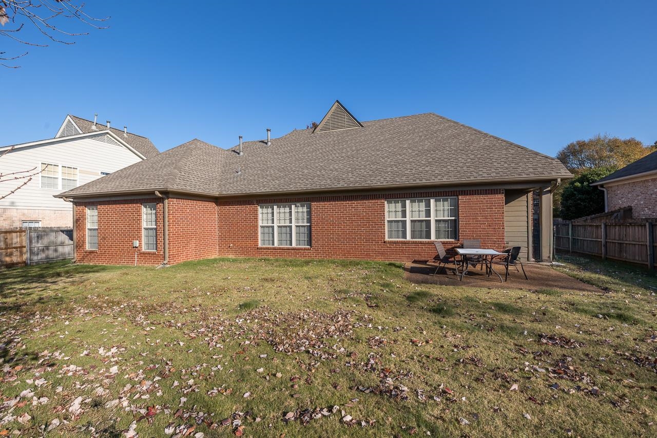 Rear view of property with a lawn and a patio