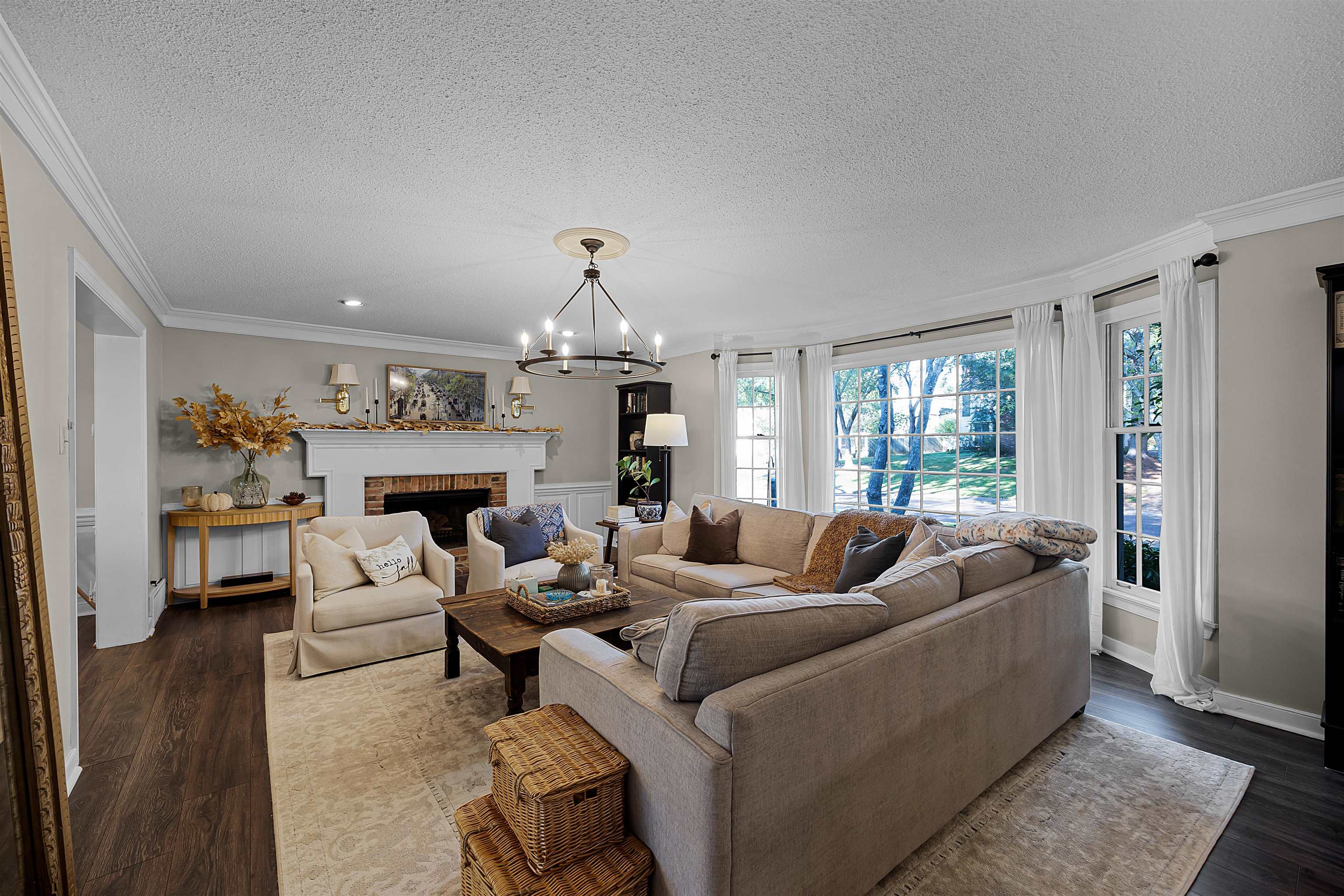 Living room featuring a textured ceiling, crown molding, dark hardwood / wood-style floors, and a brick fireplace