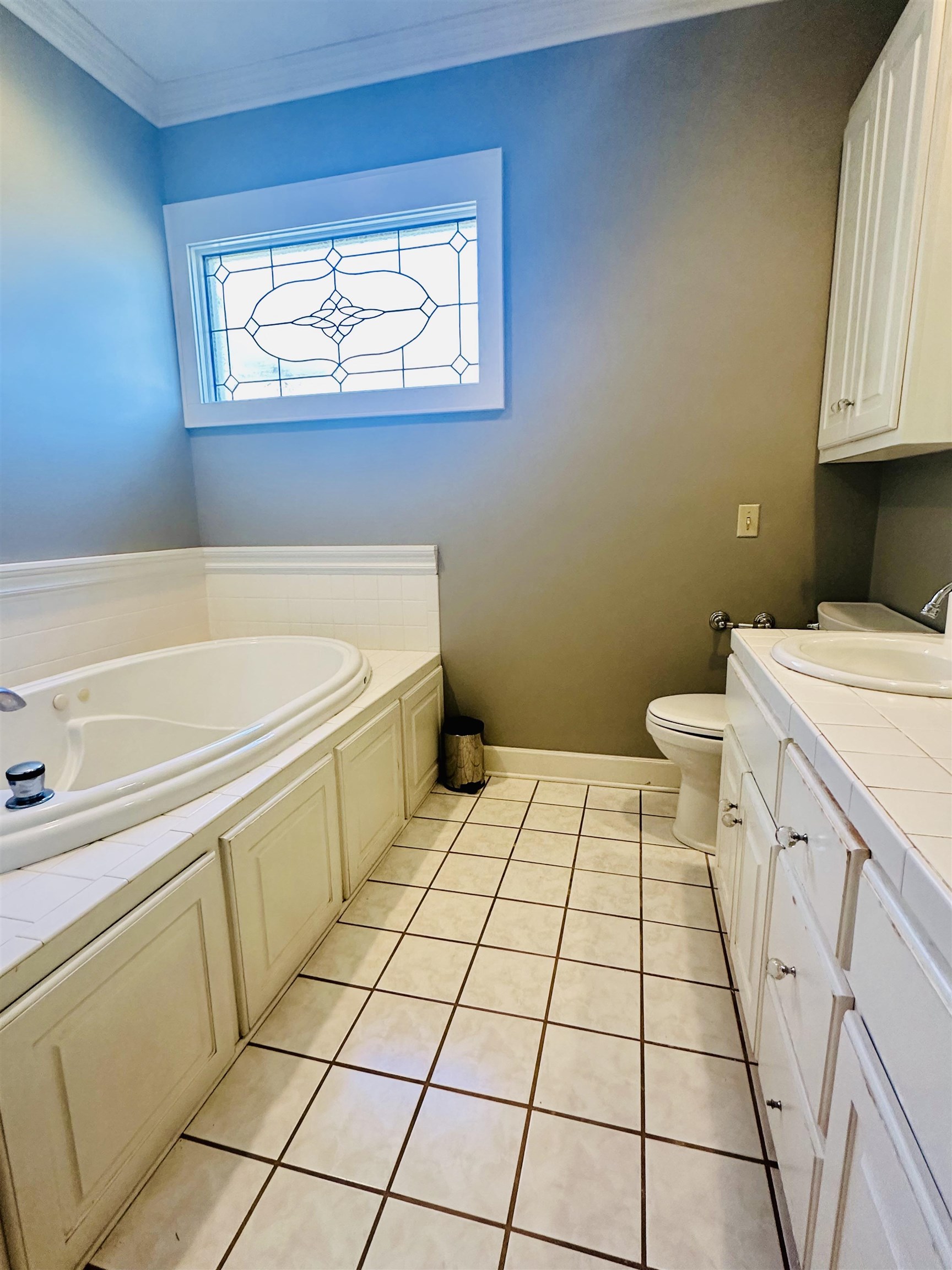 Bathroom featuring tile patterned flooring, a tub to relax in, crown molding, toilet, and vanity