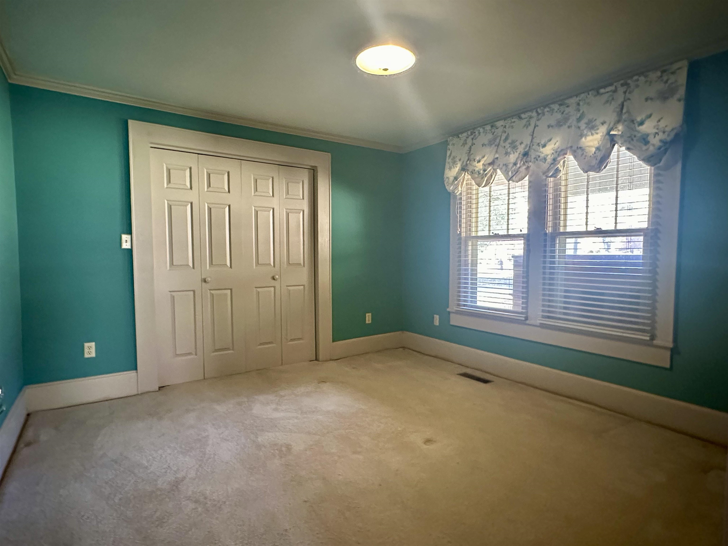 Unfurnished bedroom with carpet floors, crown molding, and a closet