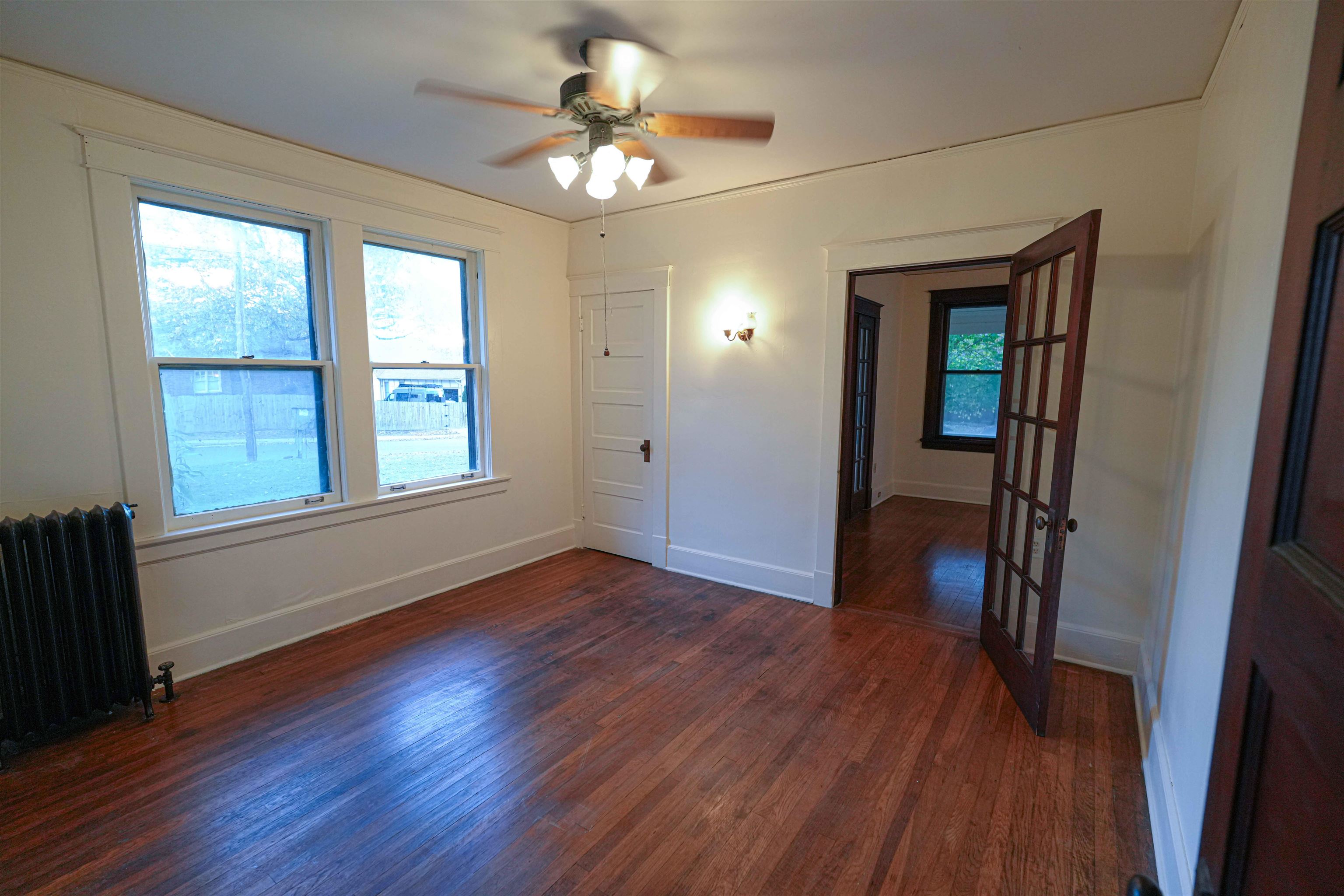 Unfurnished room featuring dark wood-type flooring, radiator, a healthy amount of sunlight, and ceiling fan