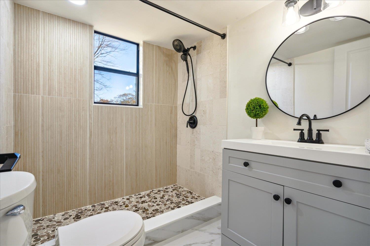 Bathroom with vanity, toilet, and tiled shower