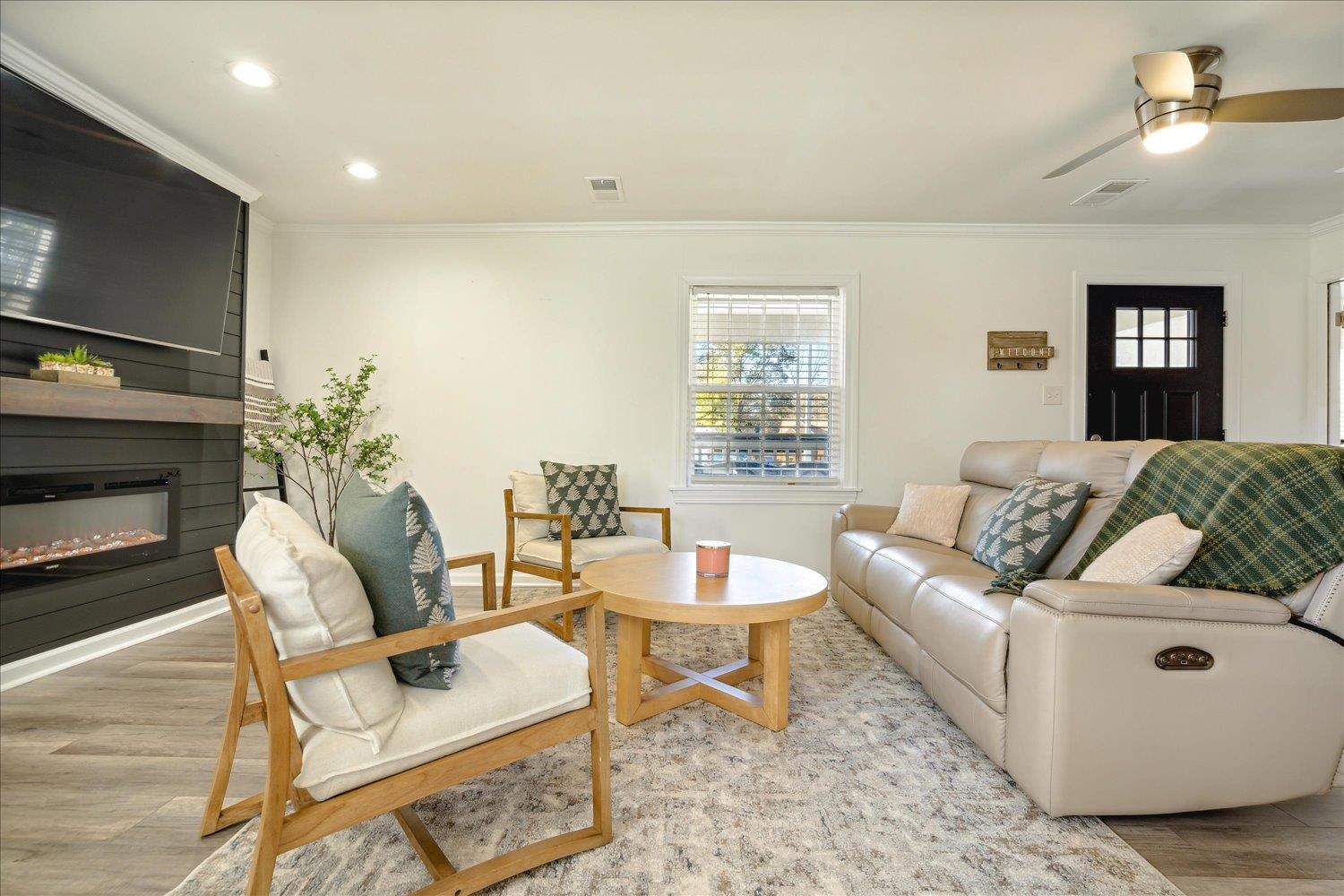 Living room featuring a fireplace, light hardwood / wood-style flooring, ceiling fan, and ornamental molding