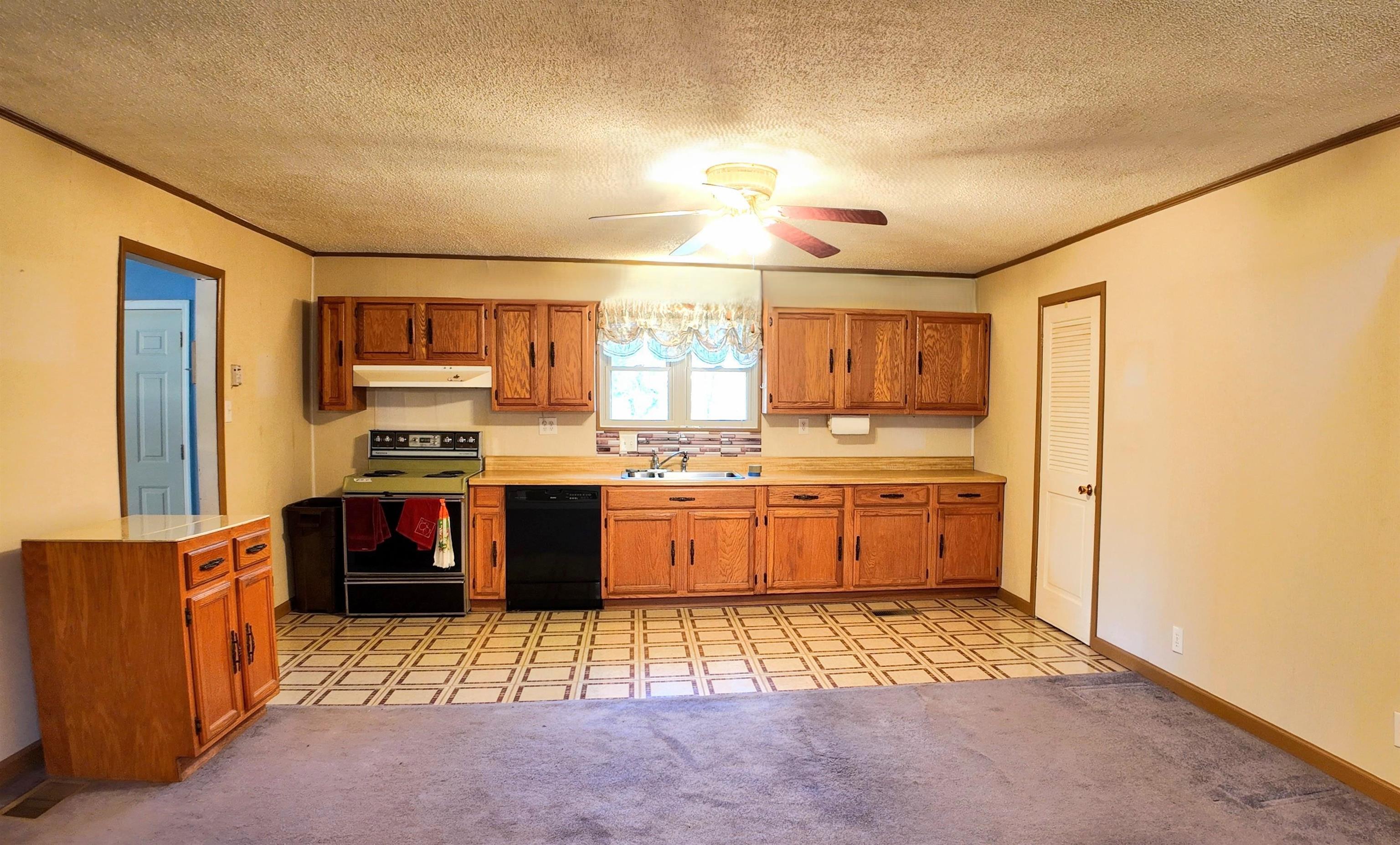 Kitchen with a textured ceiling, ceiling fan, sink, electric stove, and black dishwasher