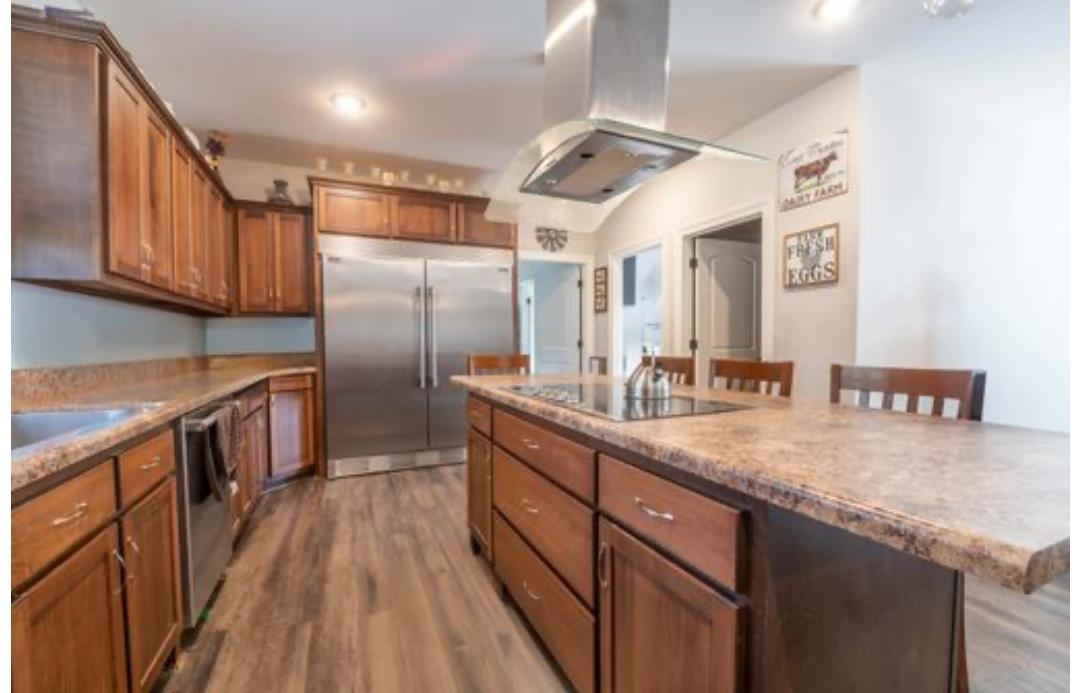 Kitchen with hardwood / wood-style floors, island range hood, a breakfast bar, and stainless steel appliances