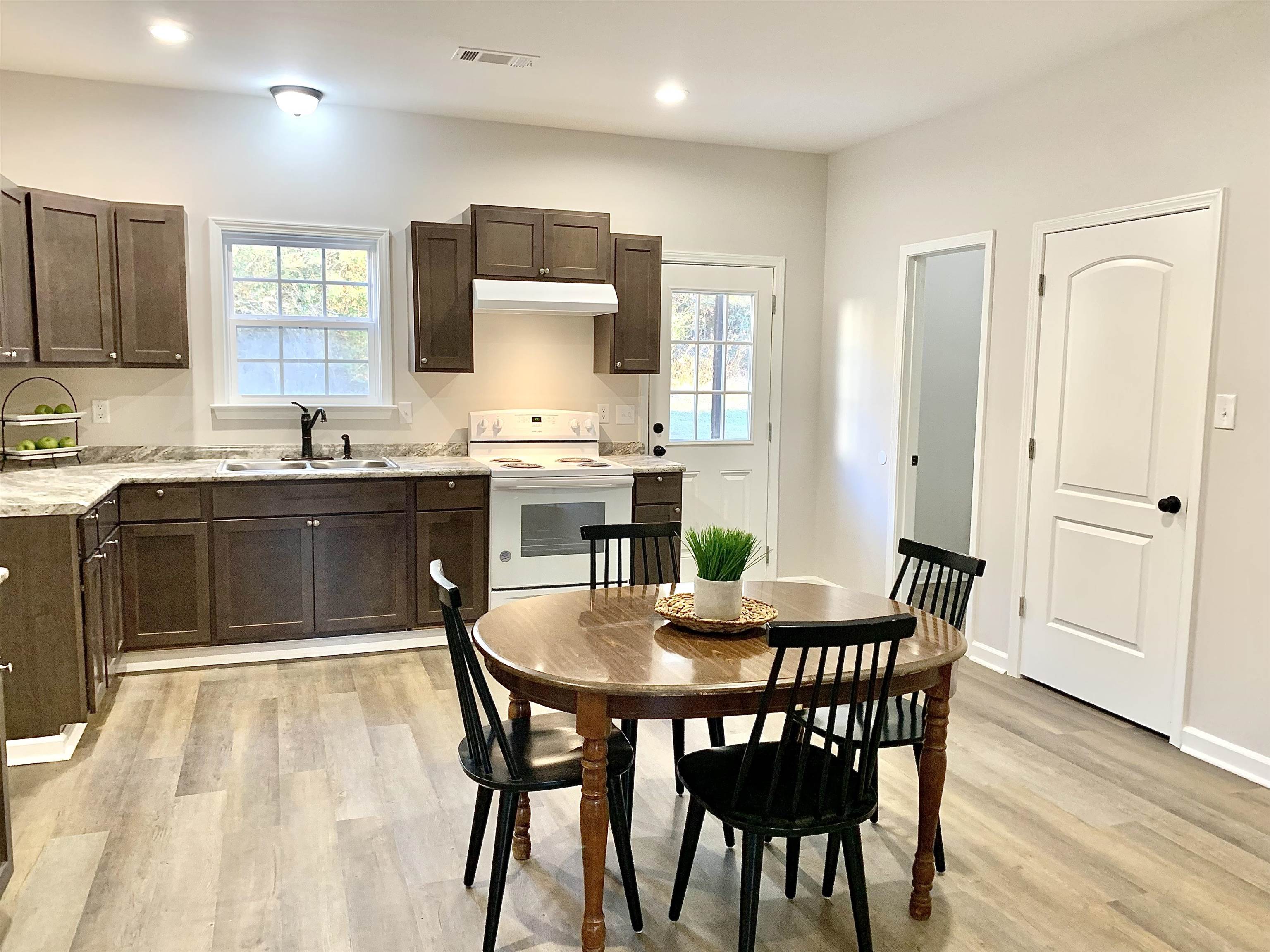 Kitchen with dark brown cabinets, electric range, light hardwood / wood-style floors, and sink