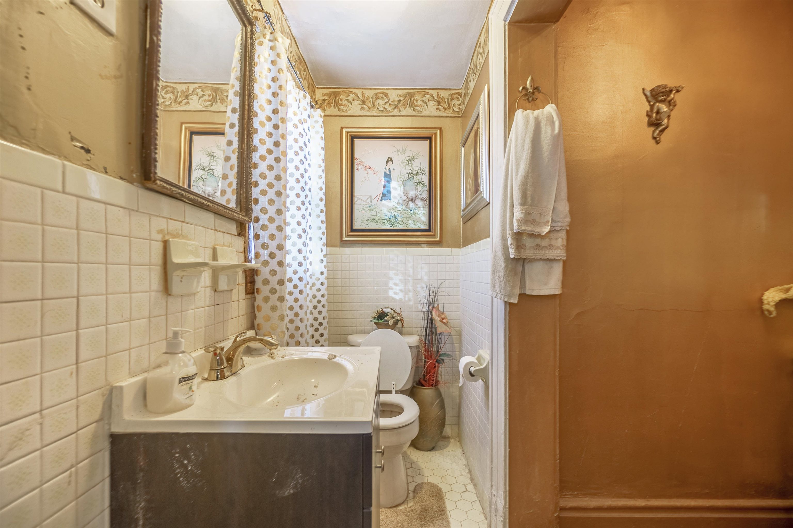 Bathroom featuring tile patterned flooring, vanity, tile walls, and toilet