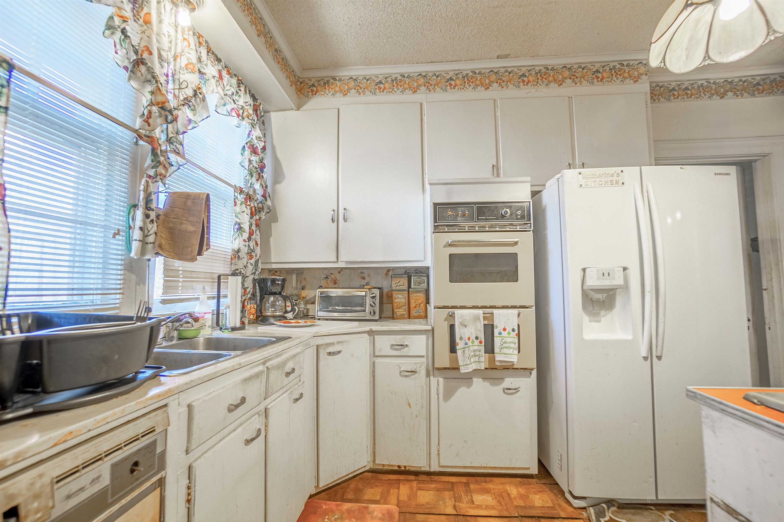 Kitchen with a textured ceiling, white appliances, crown molding, sink, and white cabinetry