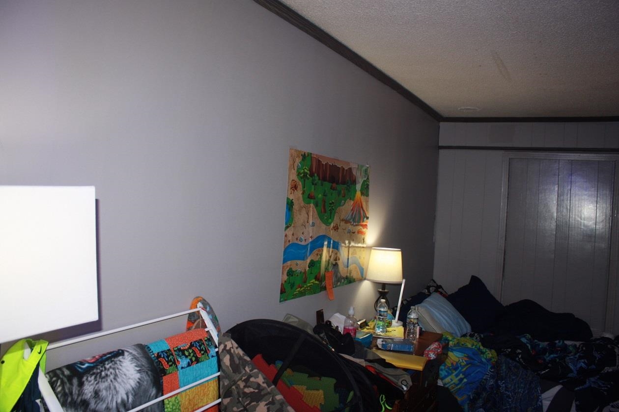 Bedroom with wood walls, a textured ceiling, and ornamental molding