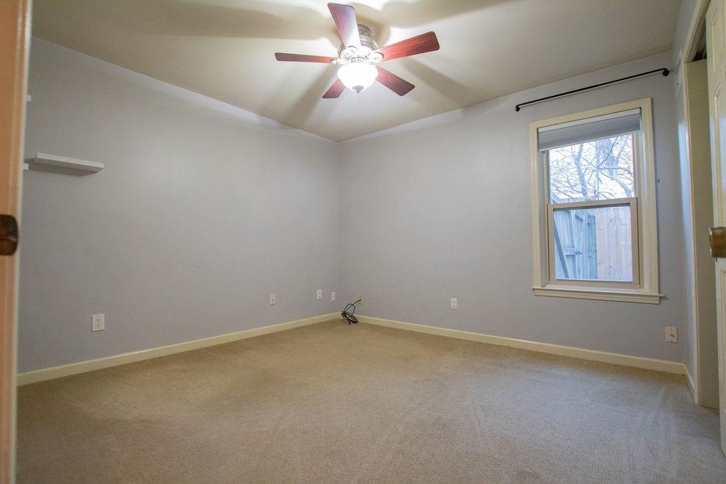 Carpeted empty room featuring ceiling fan