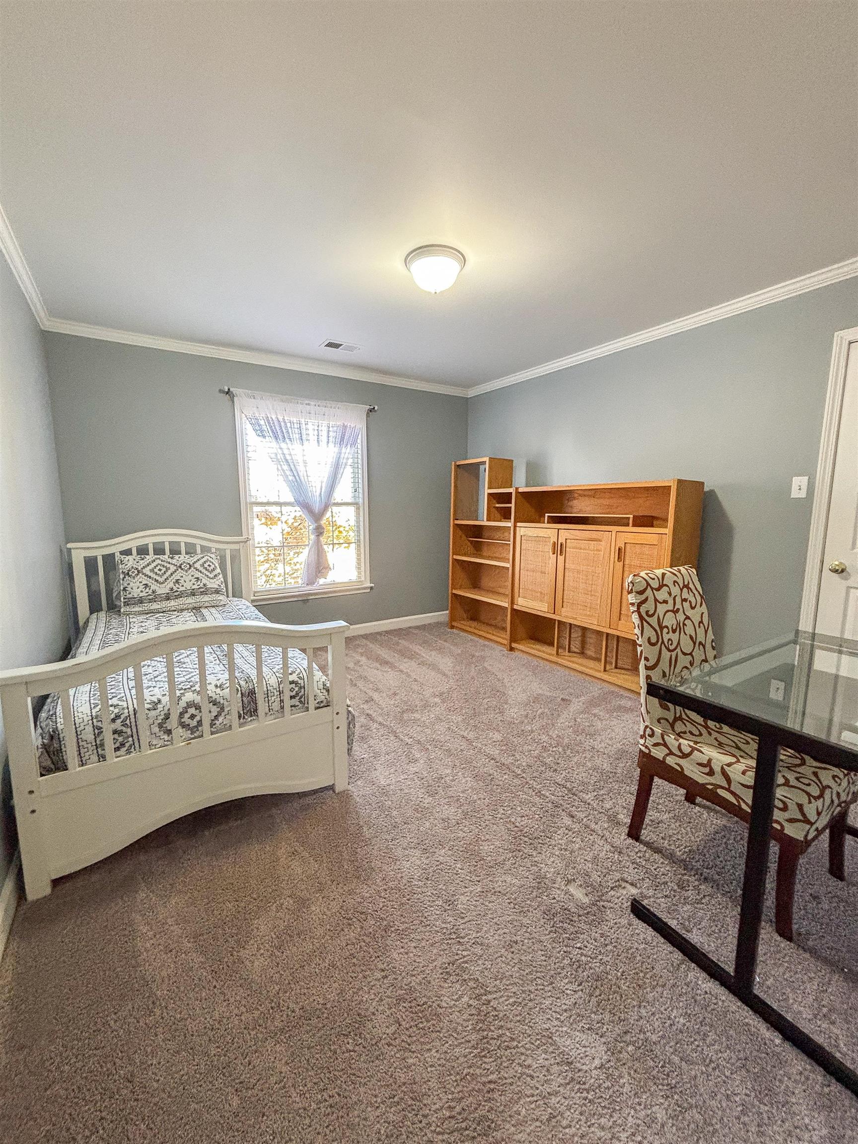 Carpeted bedroom with ornamental molding