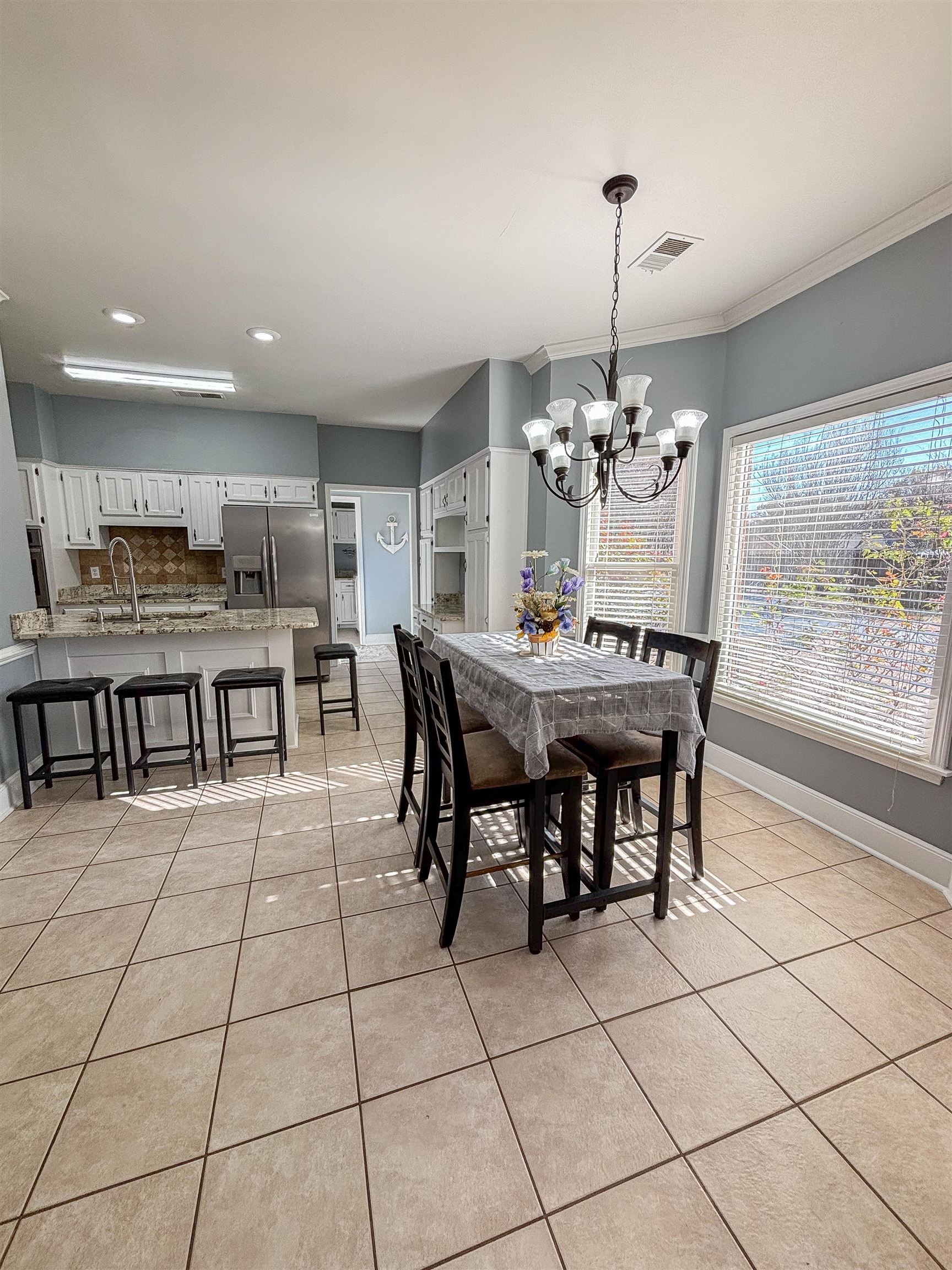 Dining room featuring crown molding, sink, light tile patterned floors, and a notable chandelier