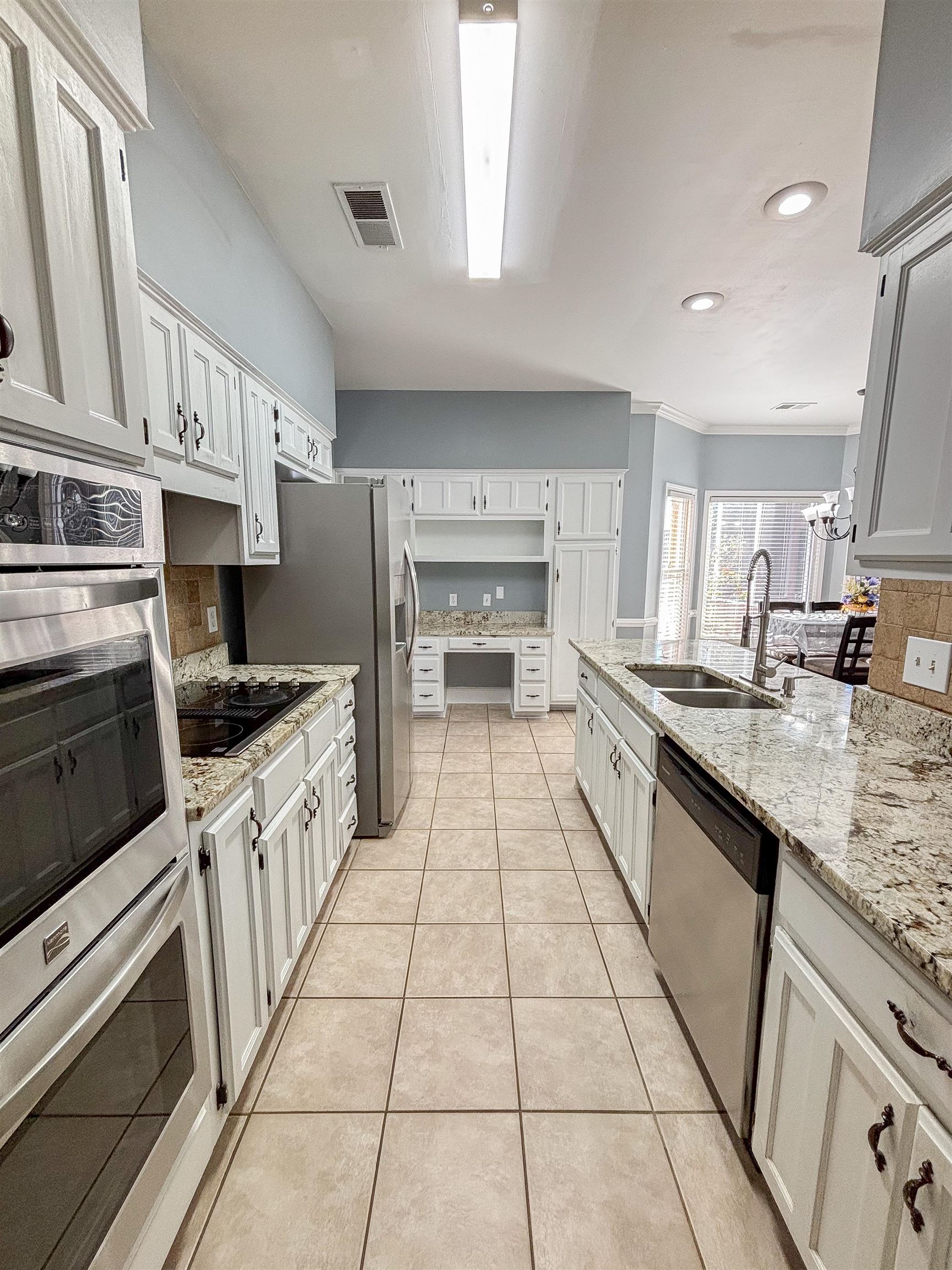 Kitchen featuring light stone countertops, white cabinetry, sink, stainless steel appliances, and light tile patterned floors