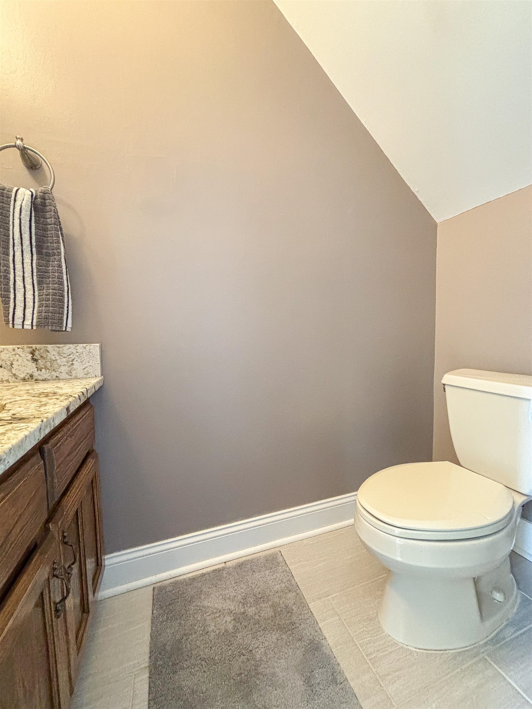 Bathroom with tile patterned flooring, vanity, vaulted ceiling, and toilet