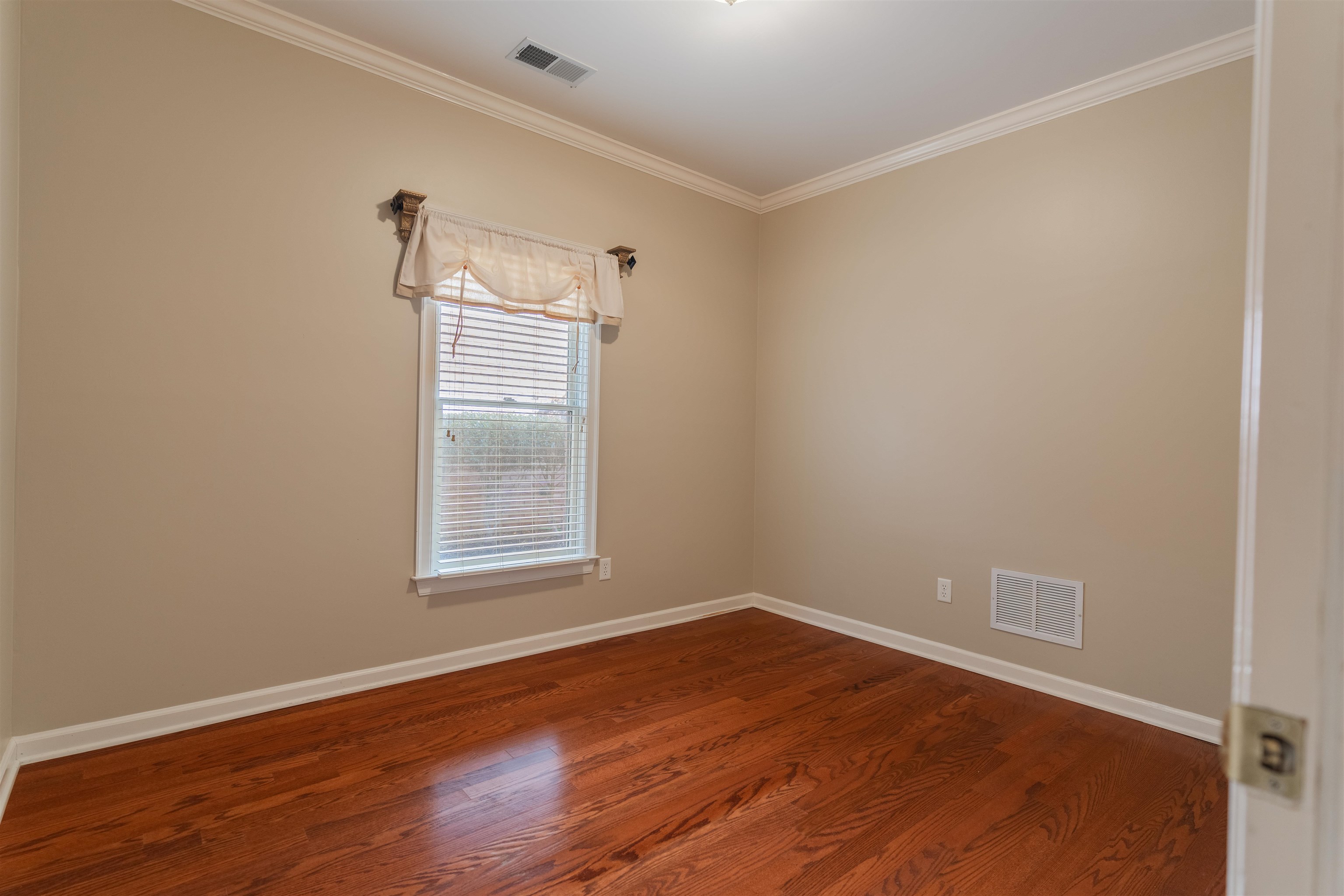 Spare room featuring wood-type flooring and crown molding