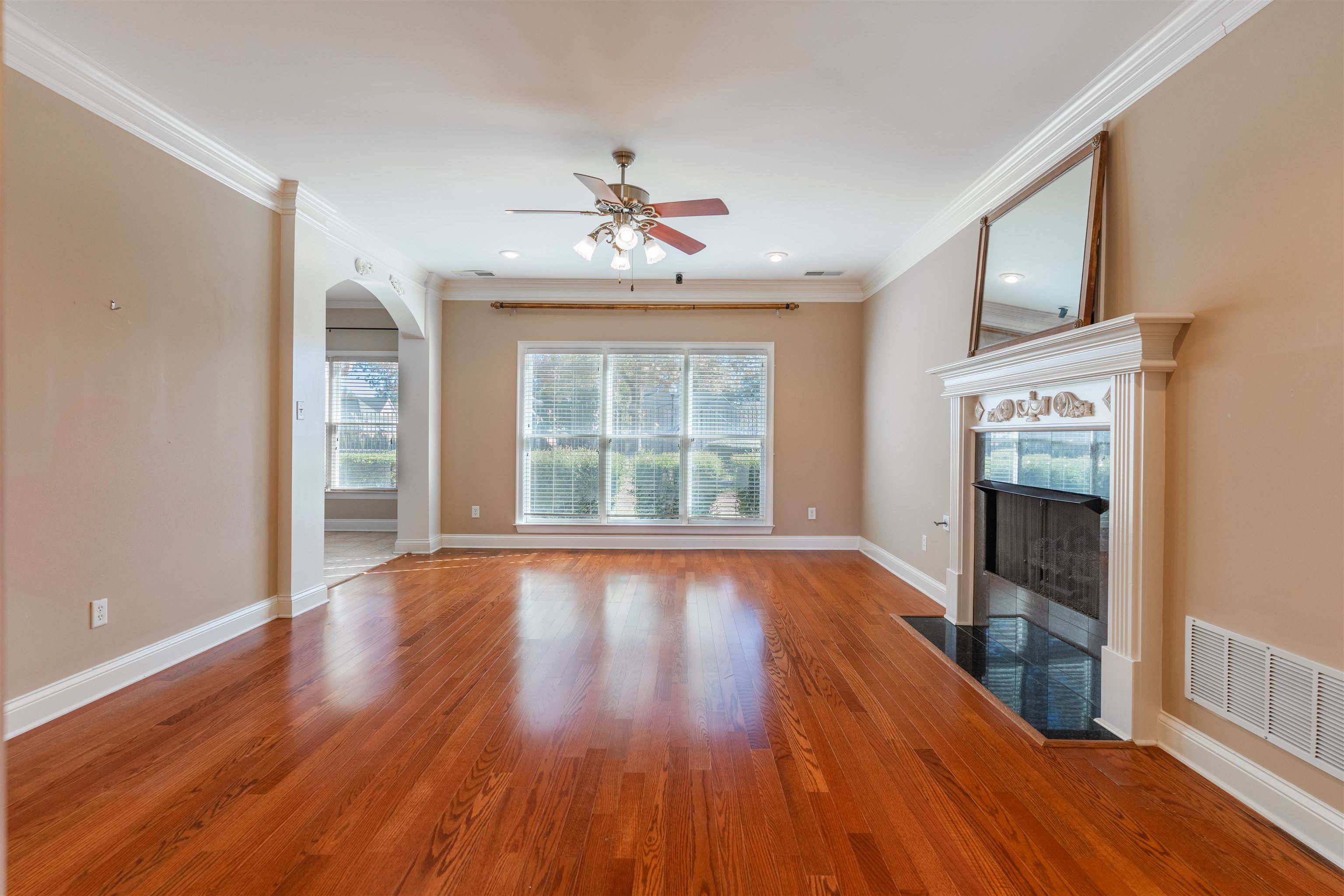 Unfurnished living room featuring hardwood / wood-style flooring, ceiling fan, and ornamental molding