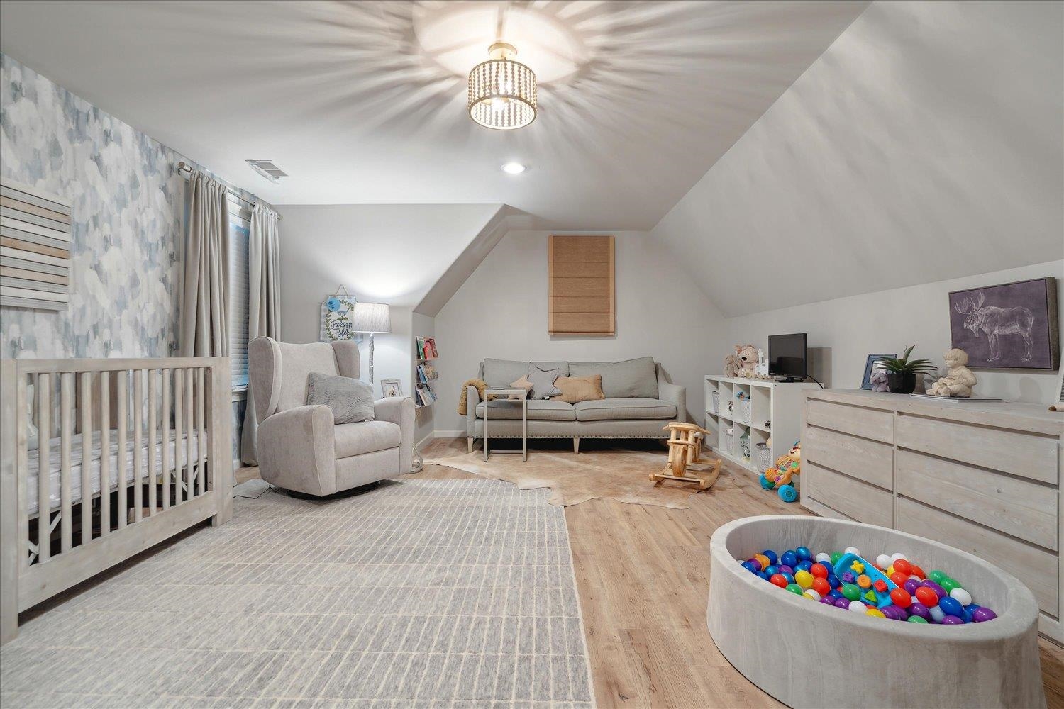 Bedroom featuring vaulted ceiling, wood-type flooring, and a nursery area