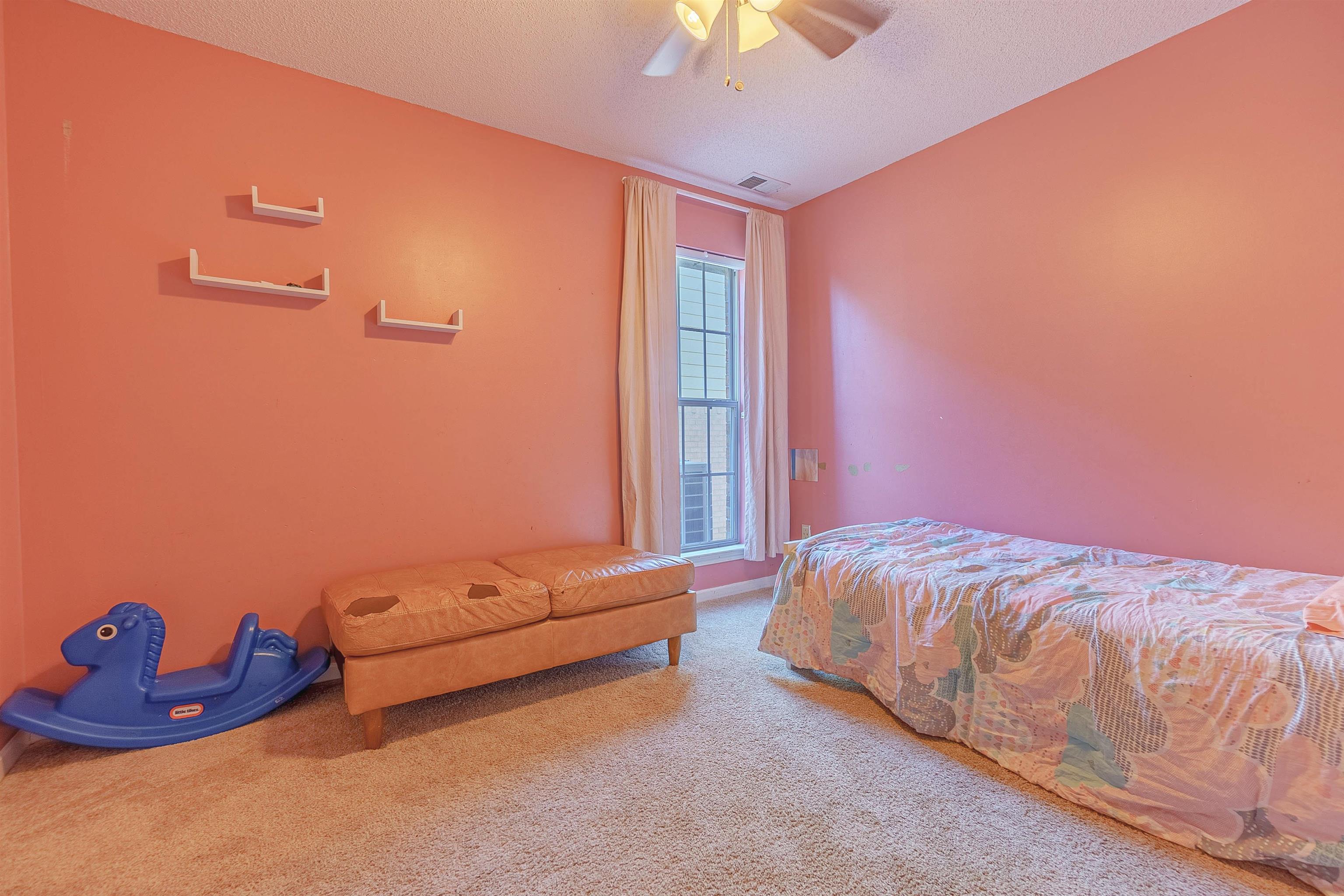 Bedroom with ceiling fan, carpet floors, and a textured ceiling