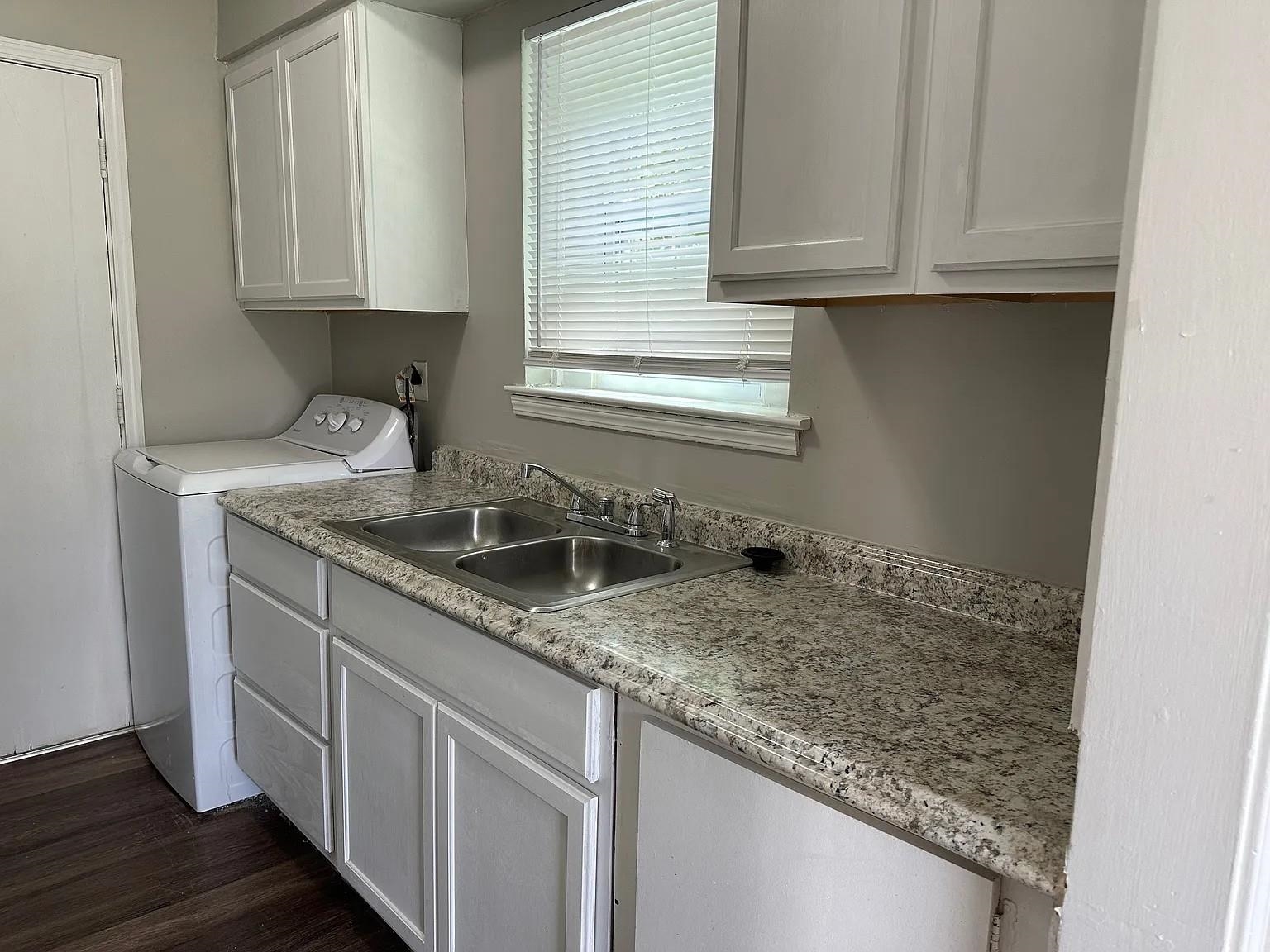 Laundry area featuring cabinets, sink, washer / clothes dryer, and dark wood-type flooring