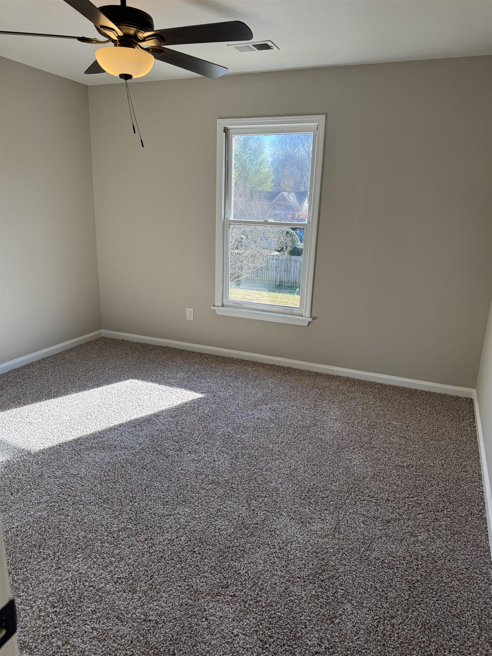 Carpeted empty room featuring ceiling fan